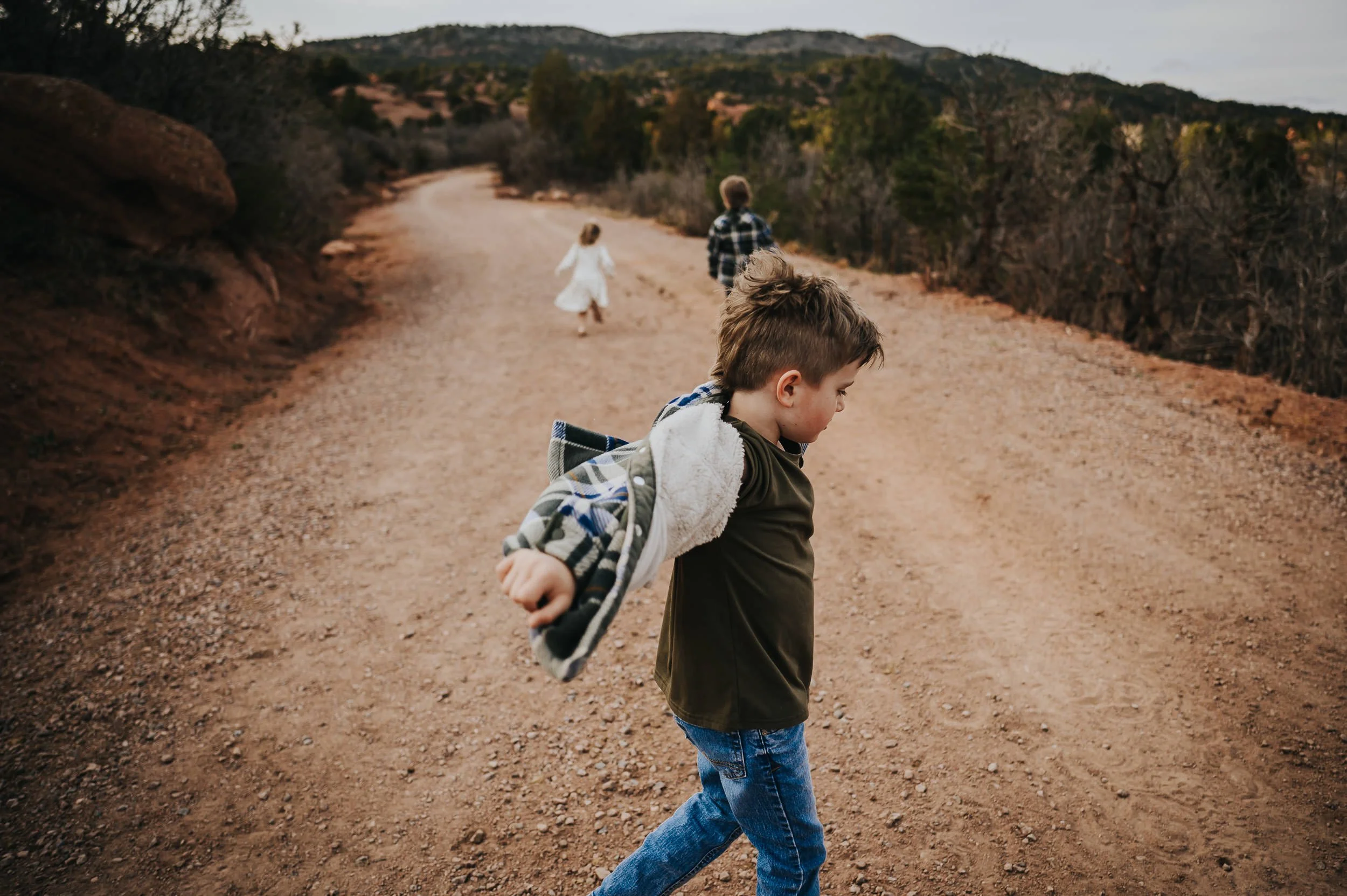 Two brothers running and playing on the red dirt trail.
