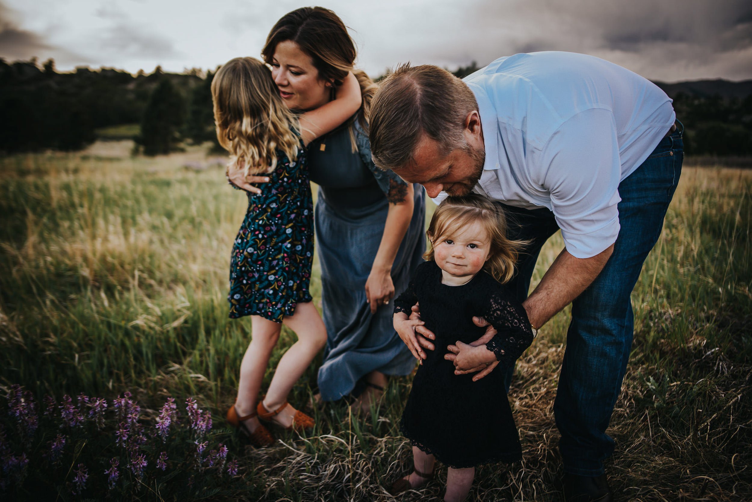 A family walks through purple wildflowers in a Colorado mountain meadow.