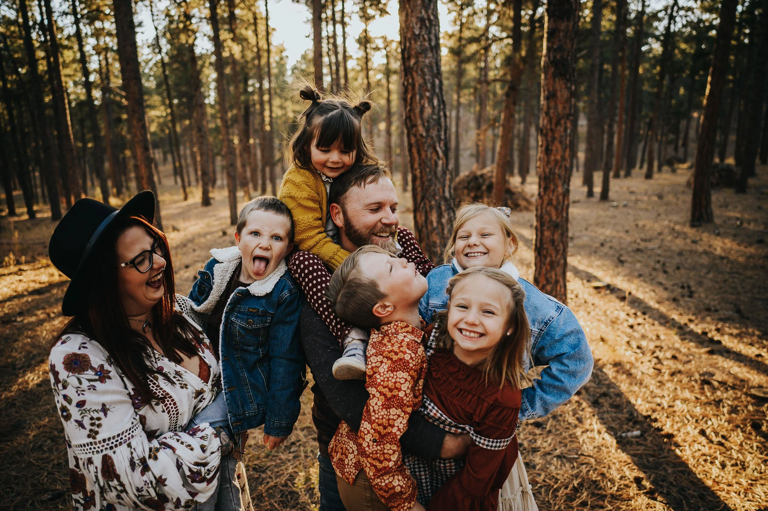 Large extended family laughing together in coordinated earth tones including rust, cream, and olive during an outdoor family session.