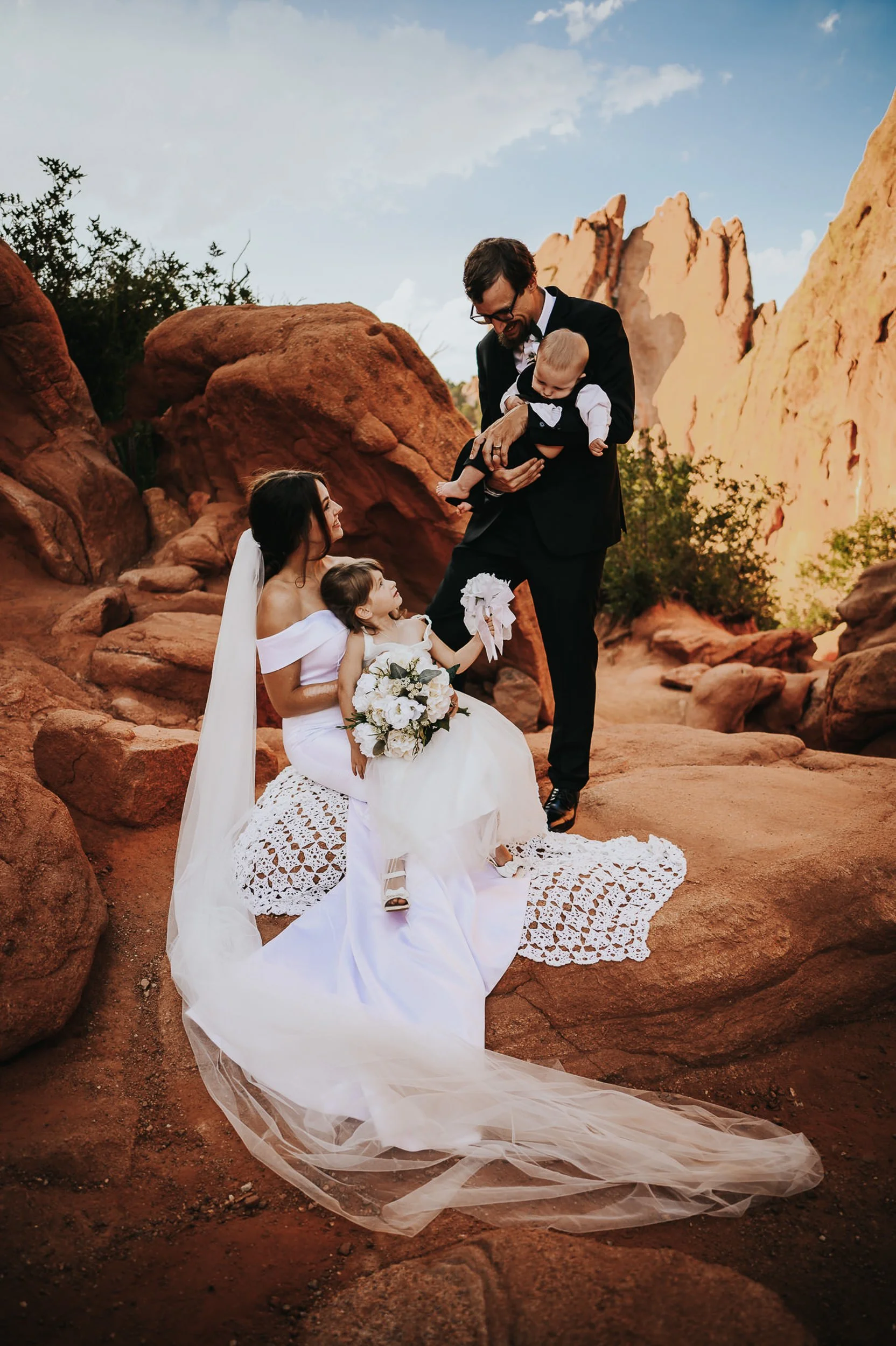Wedding ceremony at Garden of the Gods with family gathered around the couple among red rock formations.