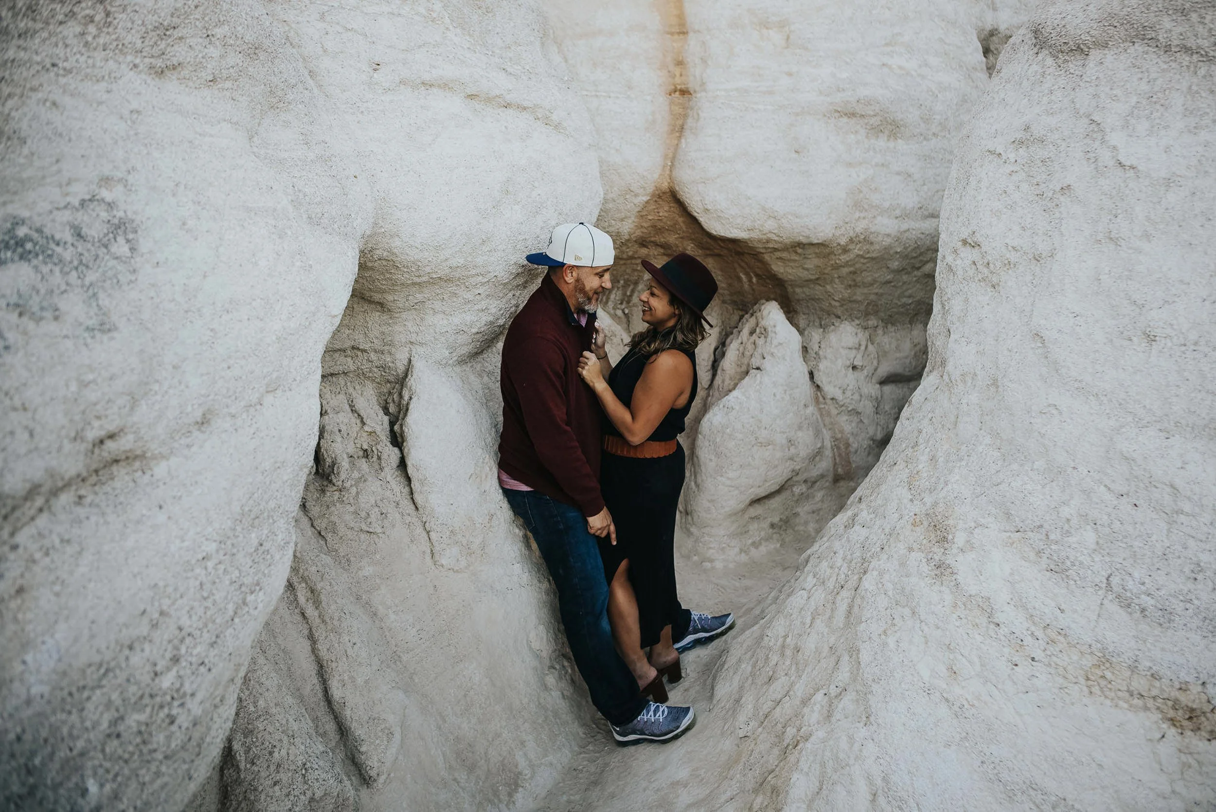 A couple shares a quiet embrace inside a narrow white rock canyon, surrounded by smooth stone walls.