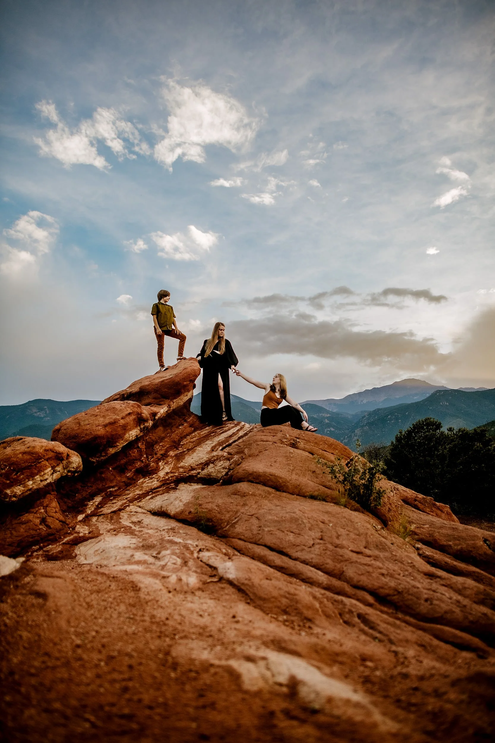 Sandy Patterson and her two kids on red rock formations at Garden of the Gods with Pikes Peak in the background.