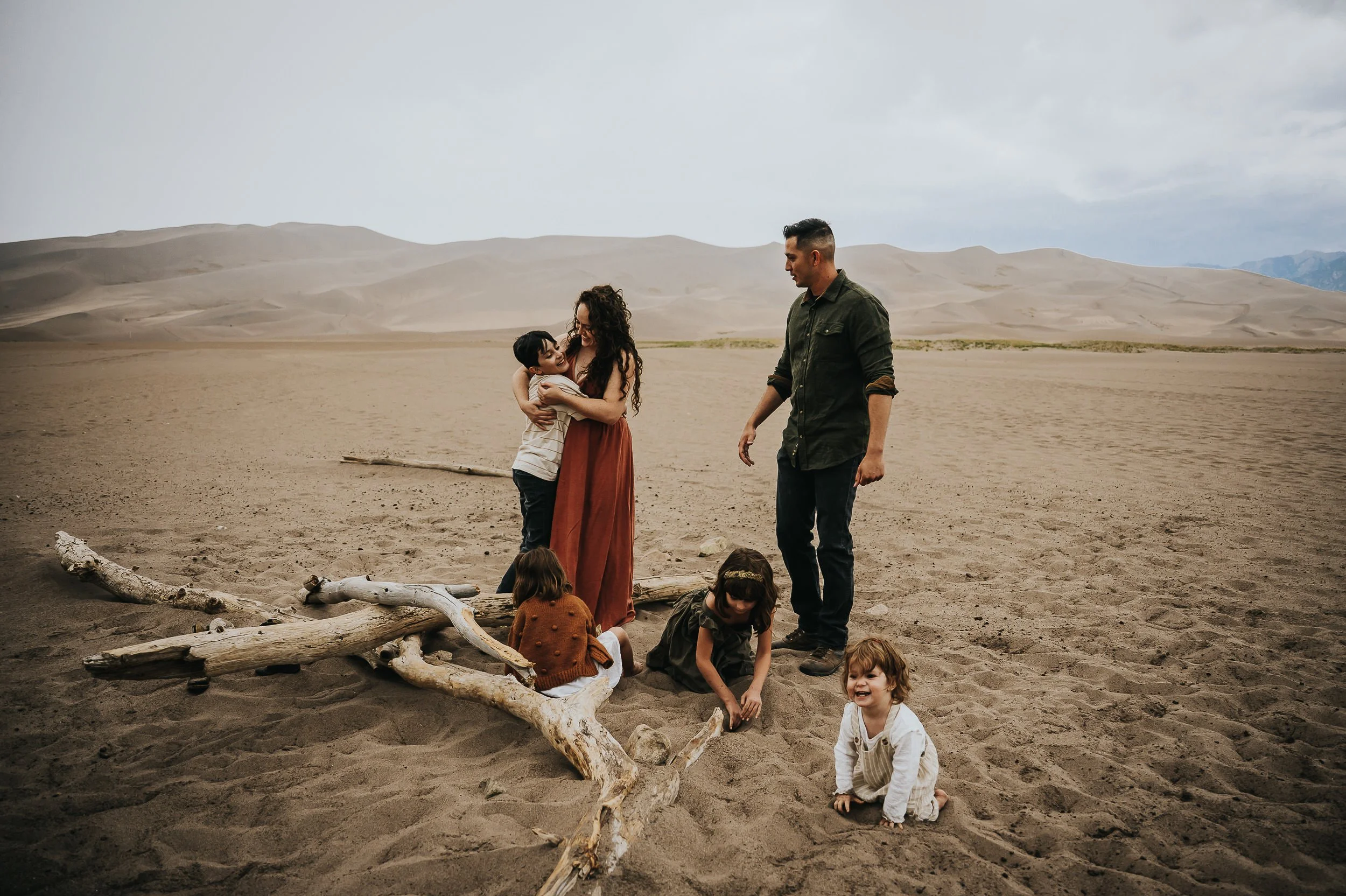 Family silhouetted against the dunes at Great Sand Dunes National Park at sunset.