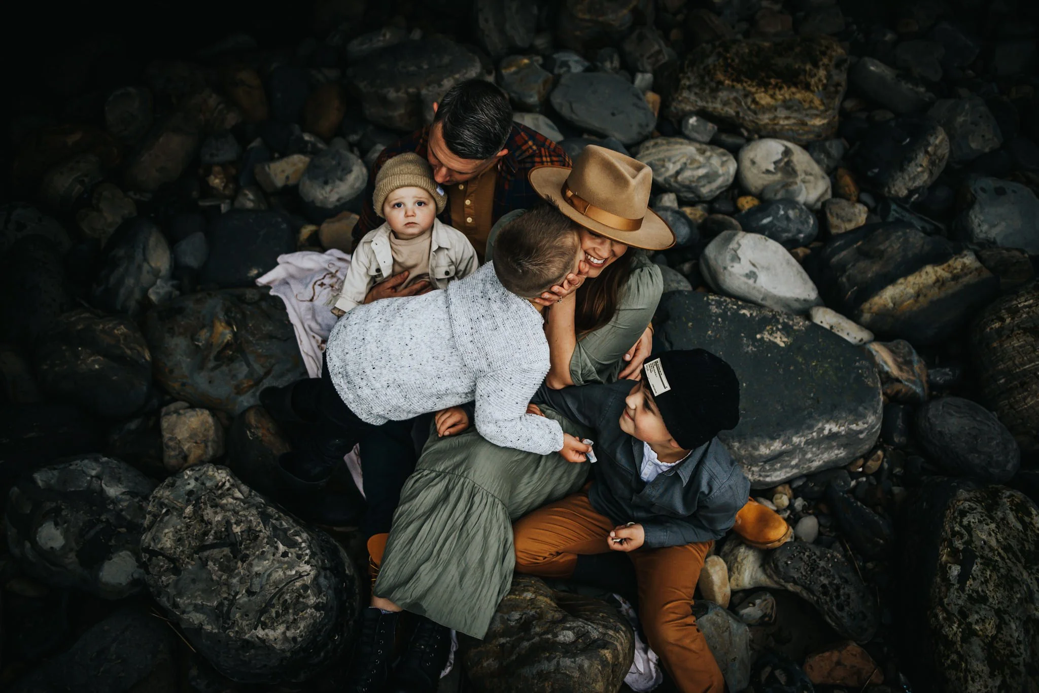Candid family photo of parents and children cuddled together outdoors, preserving everyday connection and togetherness.