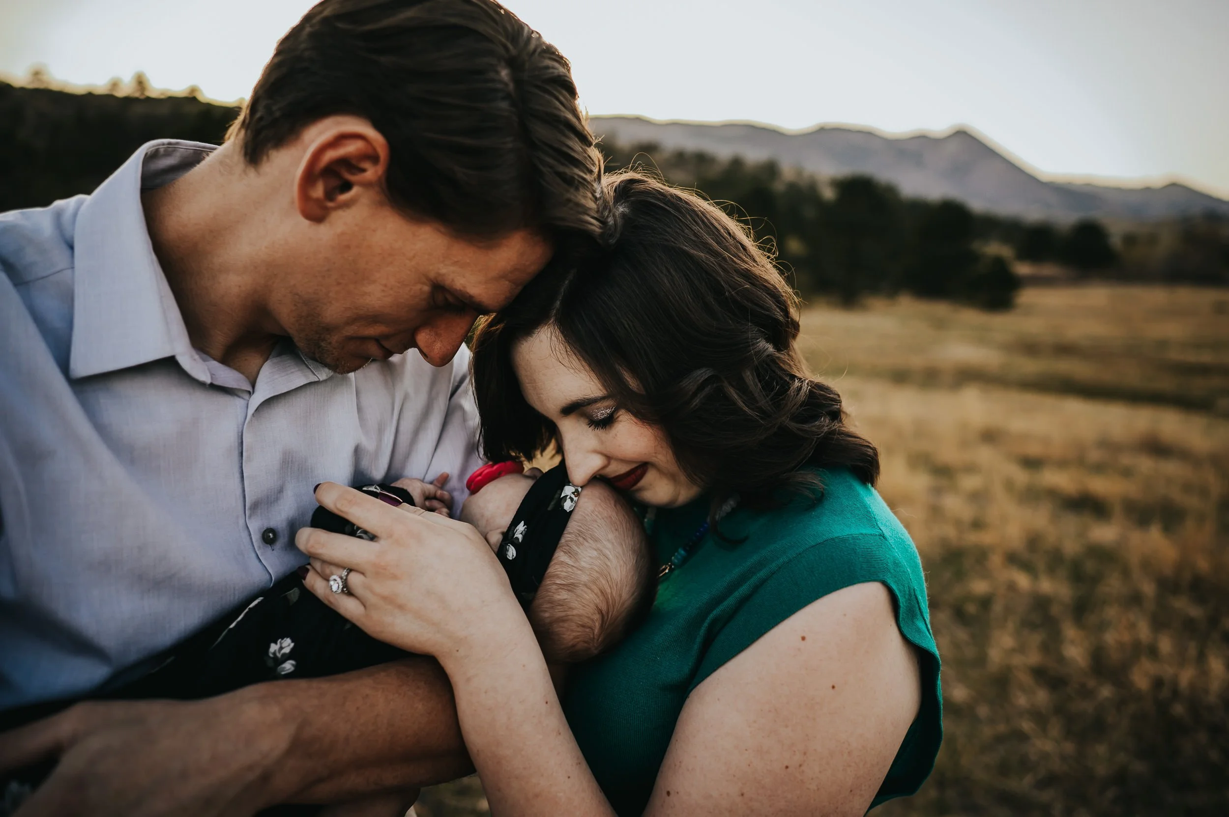 New family photographed in golden prairie grass at Ute Valley Park during newborn session.