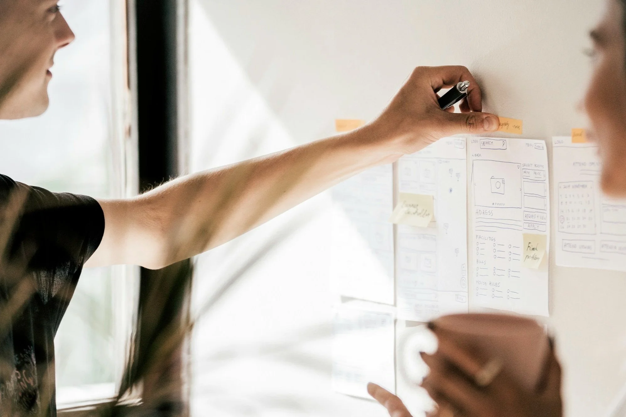 A hand putting a note on a board with other notes