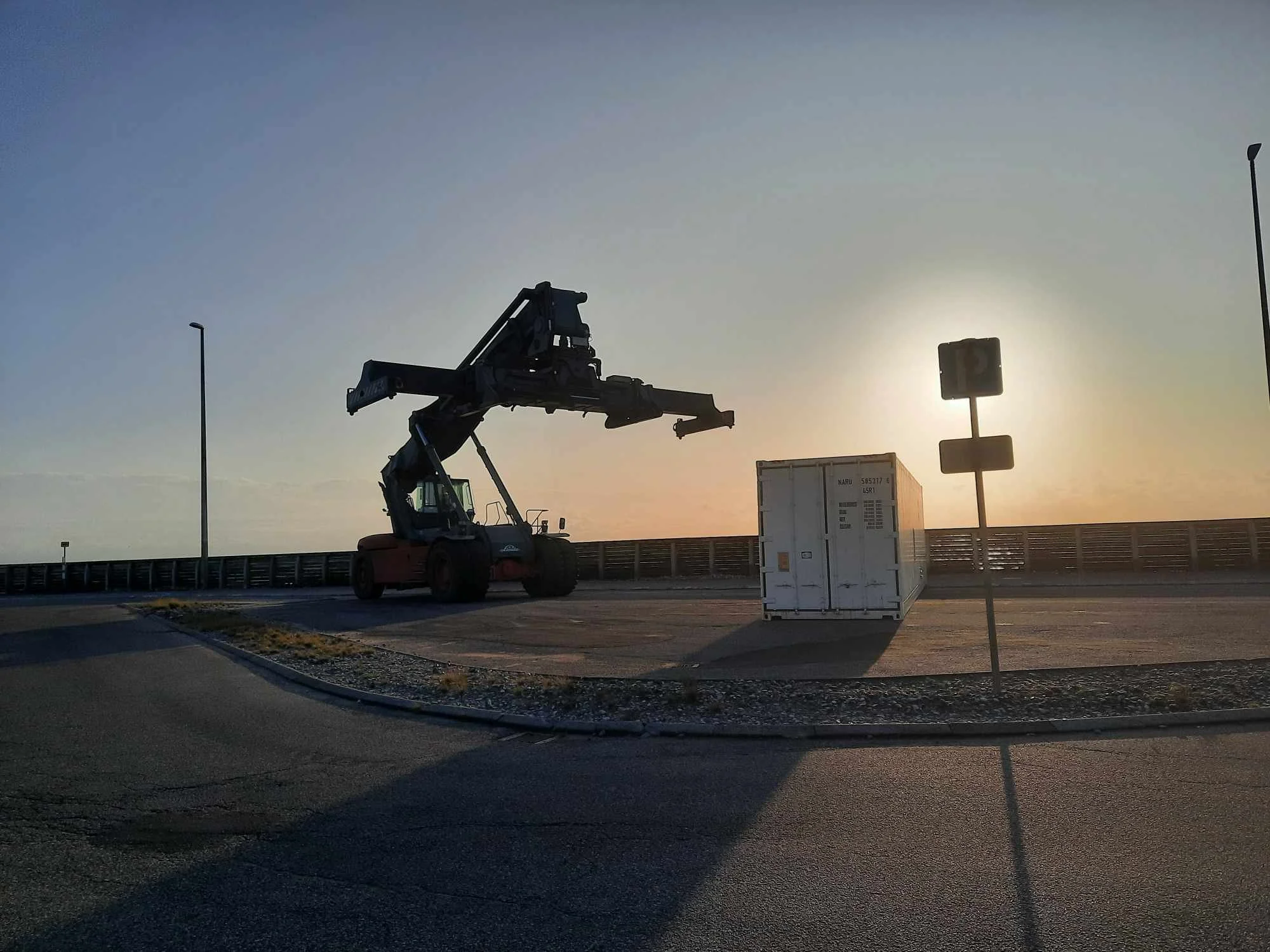 Metal ship container and lift on the road of a habour