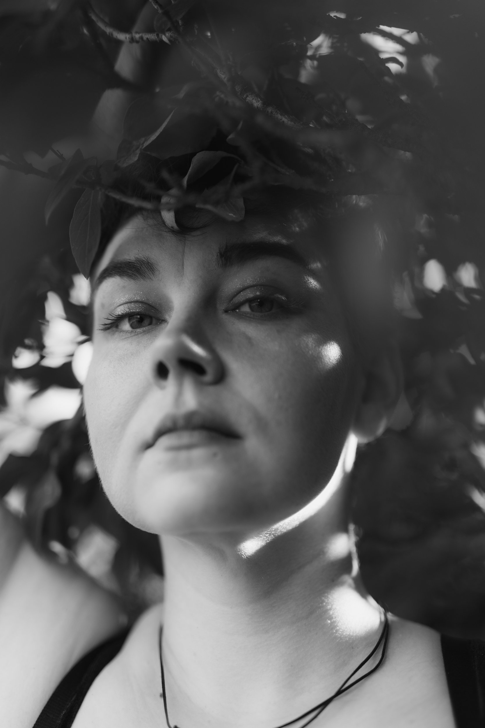 Black and white close-up photo of a person's face and upper chest, with their eyes partially closed and their hair spread out around their head.