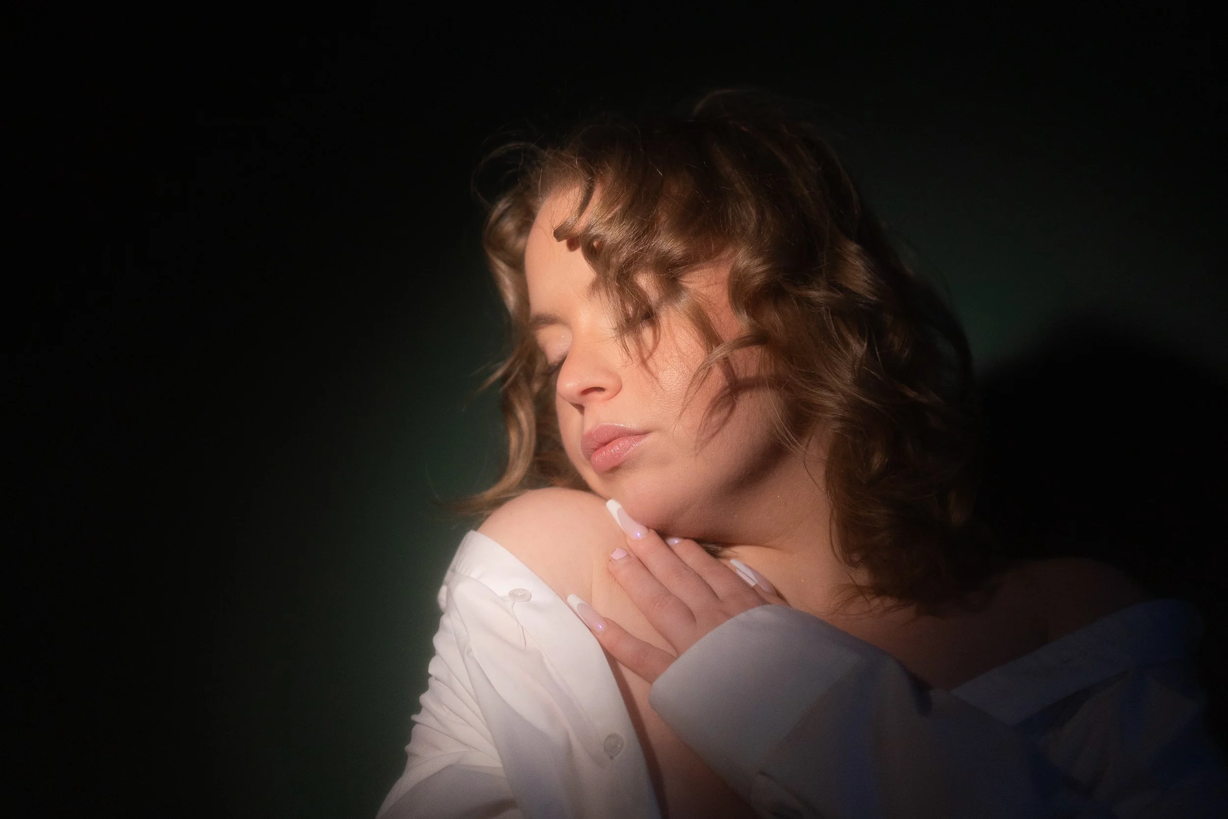 Portrait of a young woman: Her eyes are closed and she leans her chin on her shoulder.