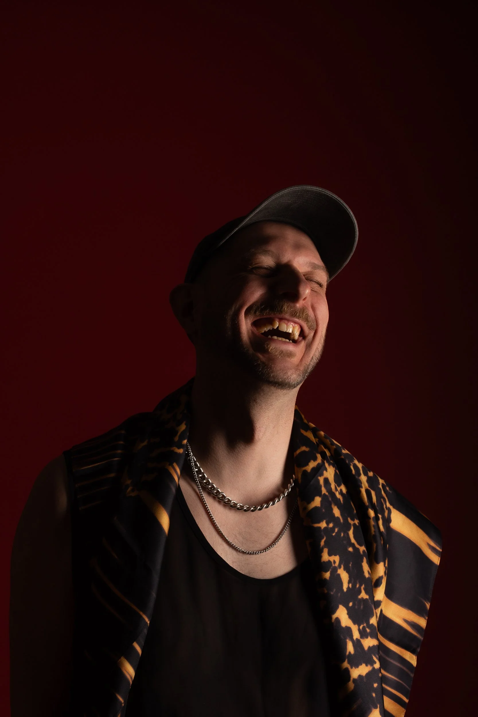 A half-lit image of a person laughing. The mood of the image is joyful and powerful. One side of the face is in shadow and the other side is in light.
