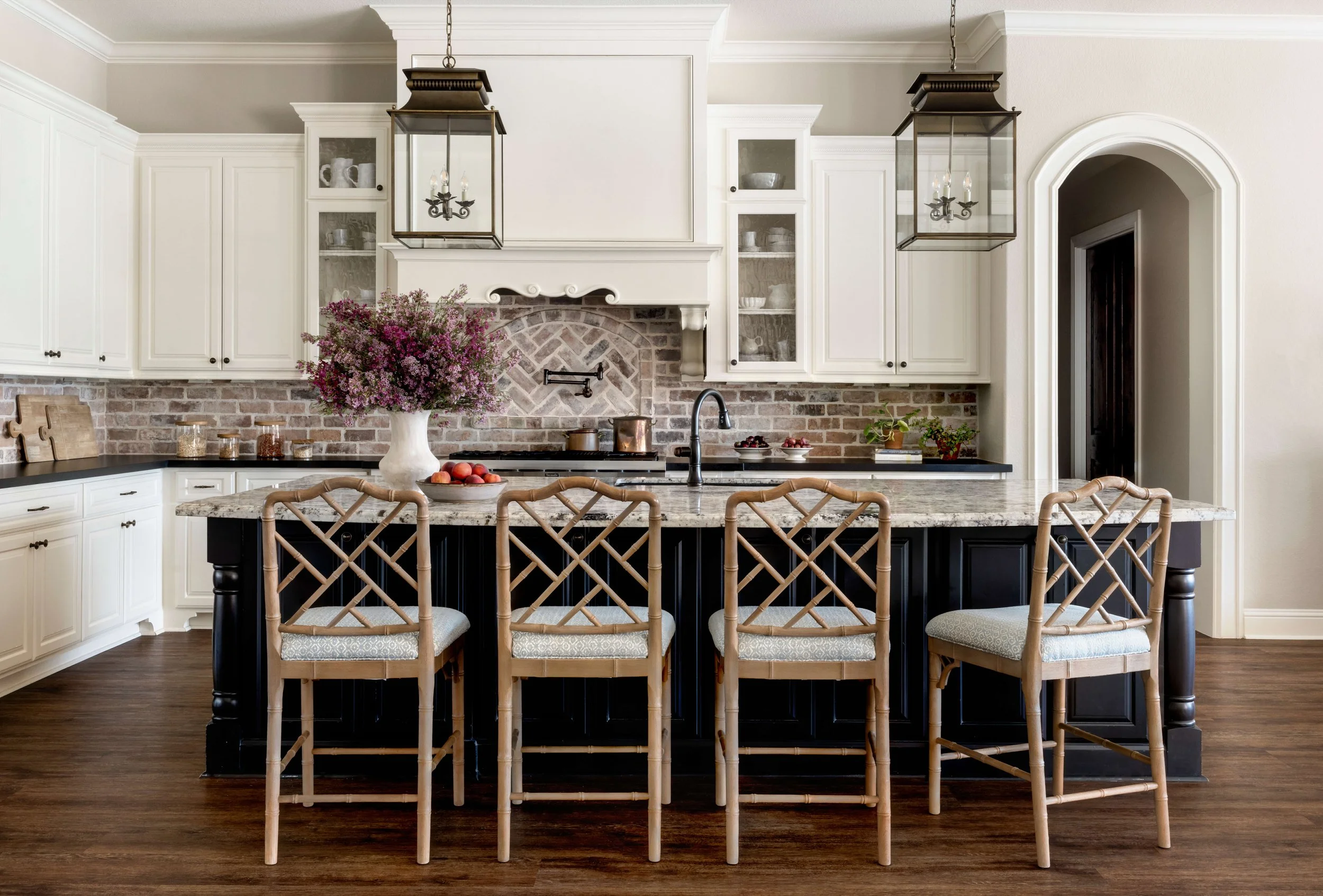 Kitchen with brick backsplash and white cabinets with lantern lighting