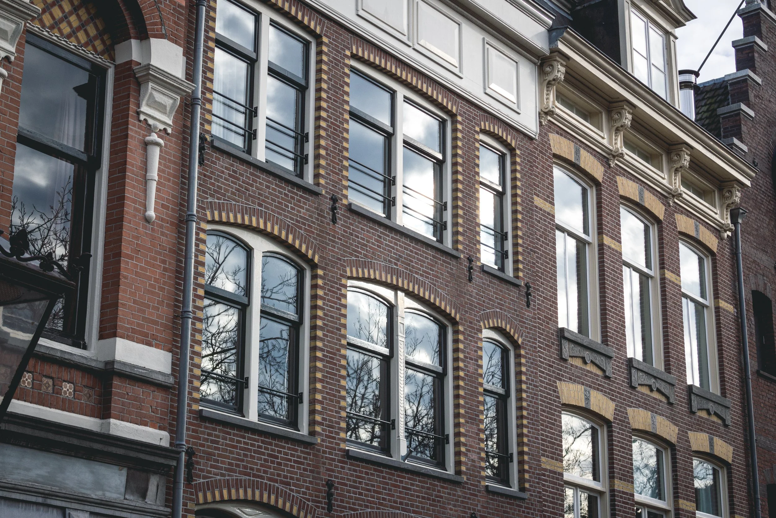 Monumentale gevel met houten kozijnen in klassieke Amsterdamse stijl – specialist in restauratie, renovatie en maatwerk kozijnen voor zakelijke projecten.