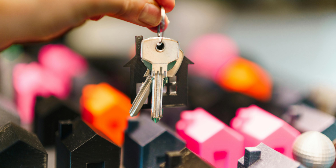 Property manager holding rental keys over colorful miniature houses, representing filling vacancies faster with email marketing for rentals