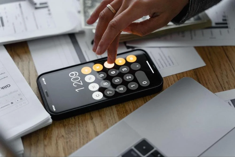 Person using a calculator to plan a commercial real estate website redesign budget