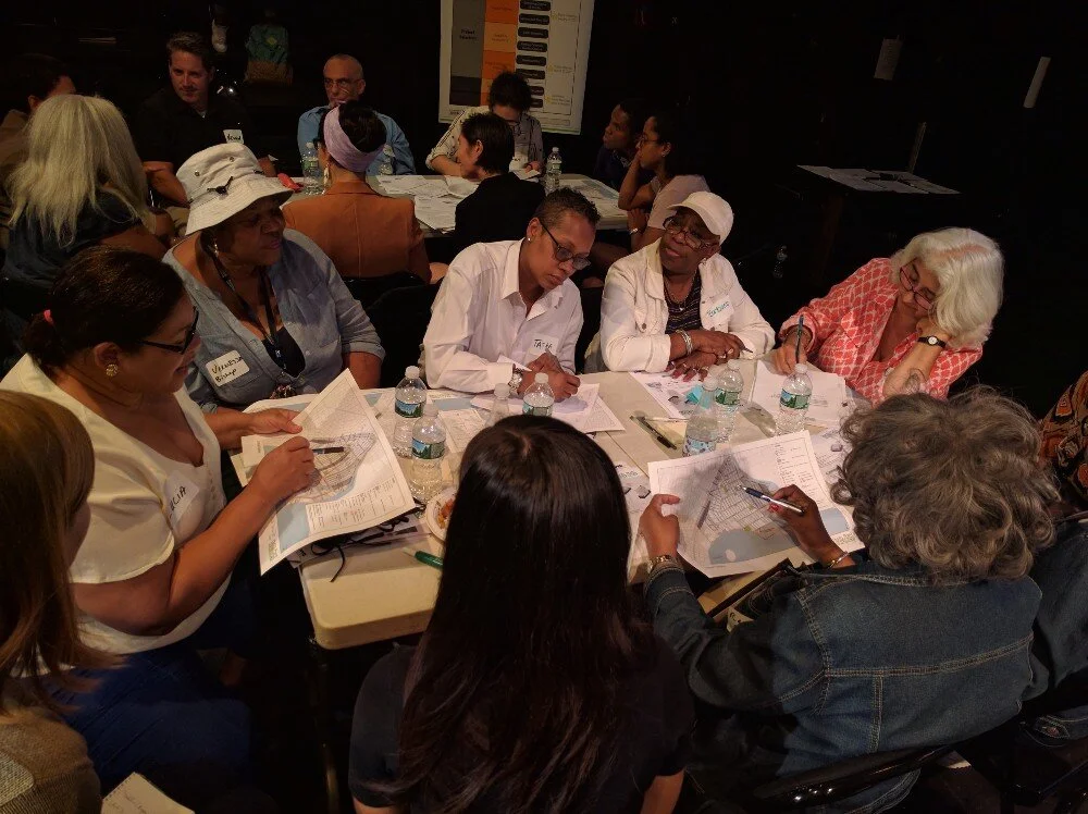 A photograph of a Hunts Point community board meeting. Community members are sitting around the table and discussing neighborhood maps. Source: EDC.