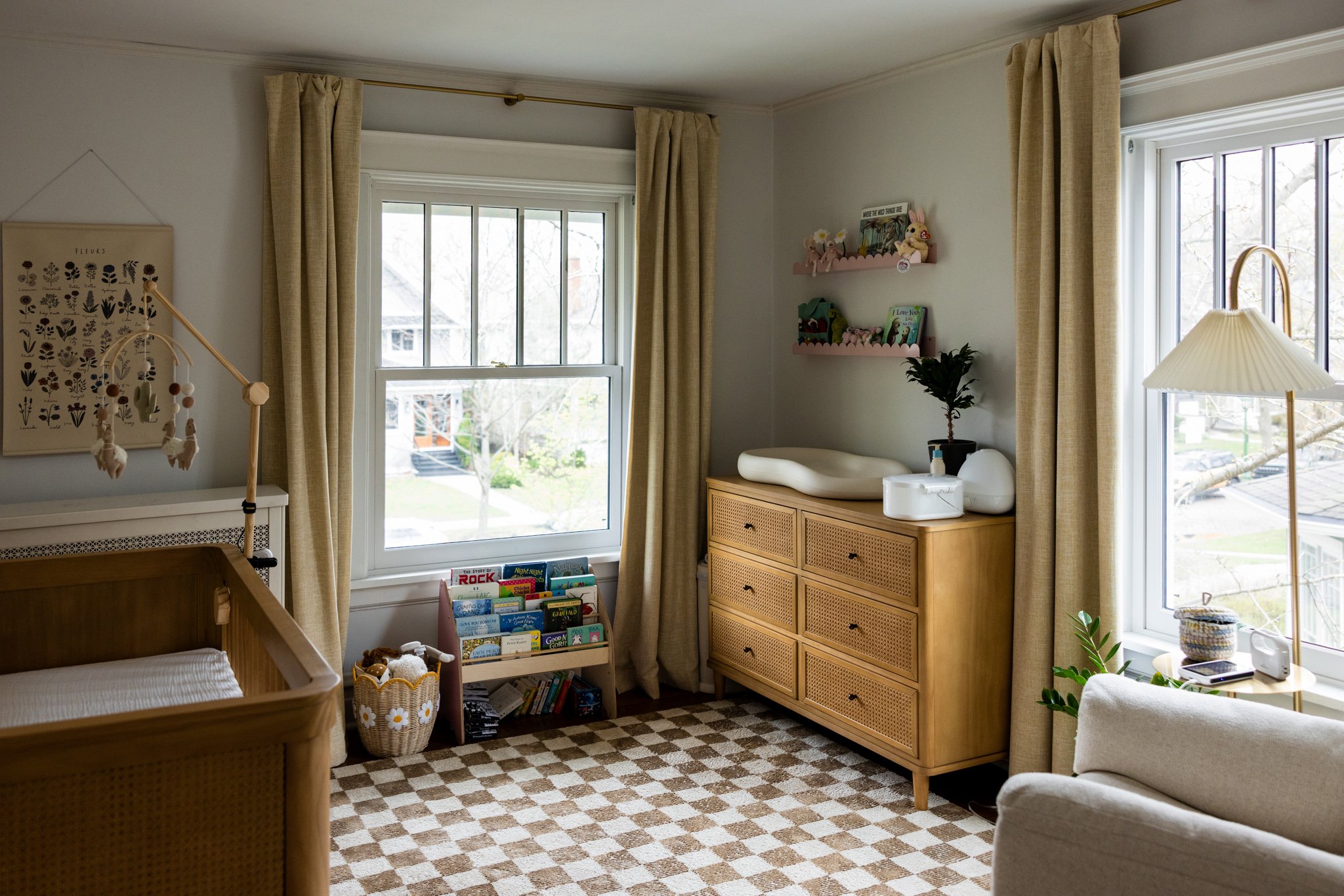 photo of a nursery decorated in neutral tones, with a checkerboard rug and wooden crib