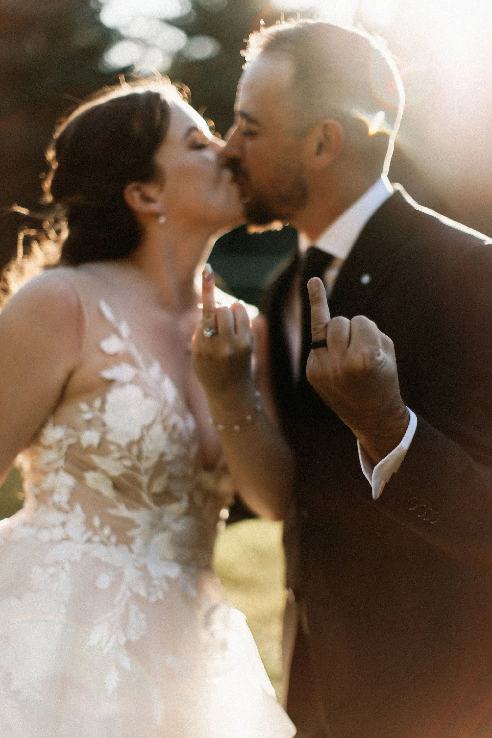 Playful bride and groom sharing a kiss at golden hour while showing off wedding rings with inTUNE Woodstock wedding DJs
