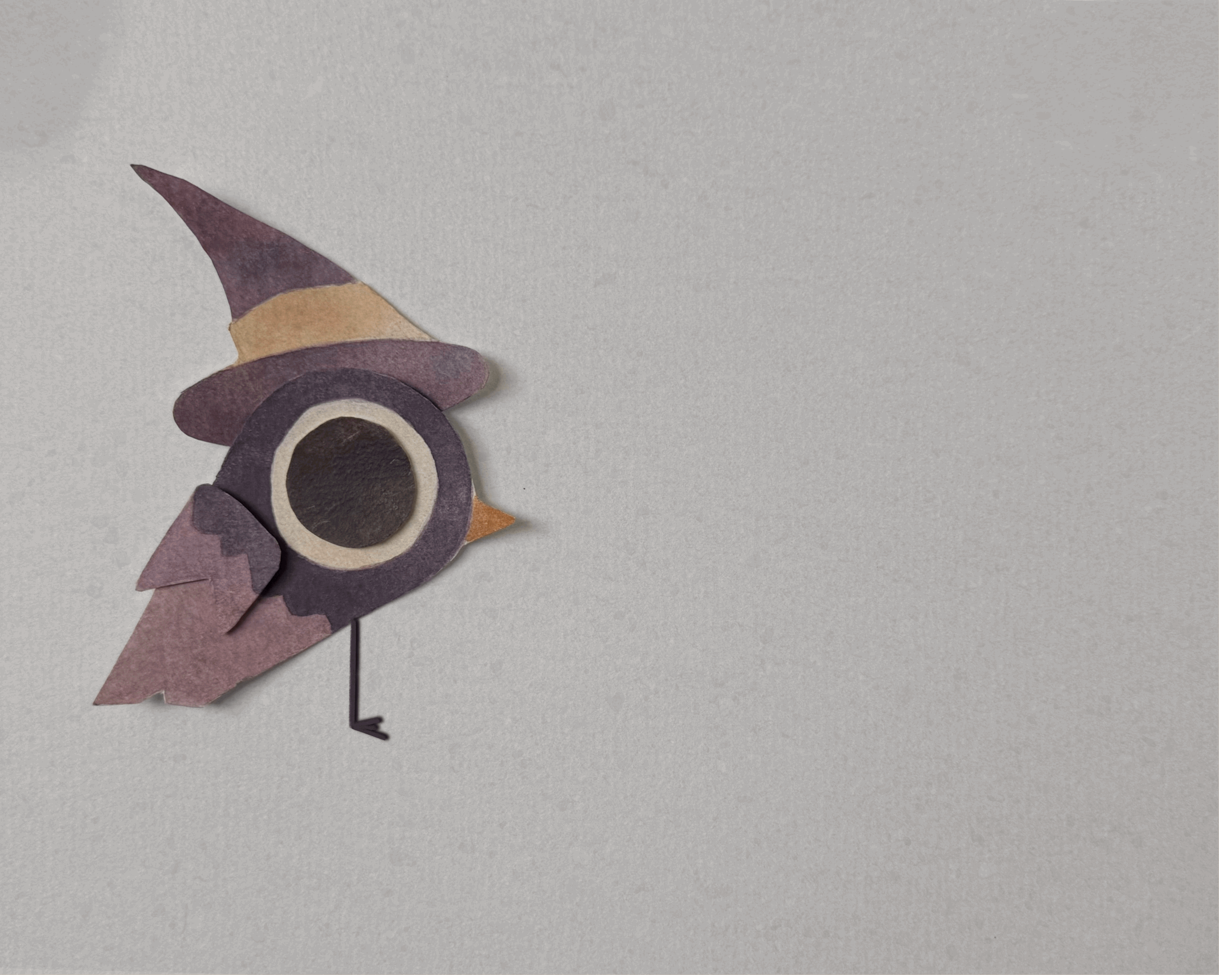 Paper craft of a colorful owl with large black eyes, a pointed beak, and pink, purple, and beige feathers, attached to a thin black stick on a plain gray background.
