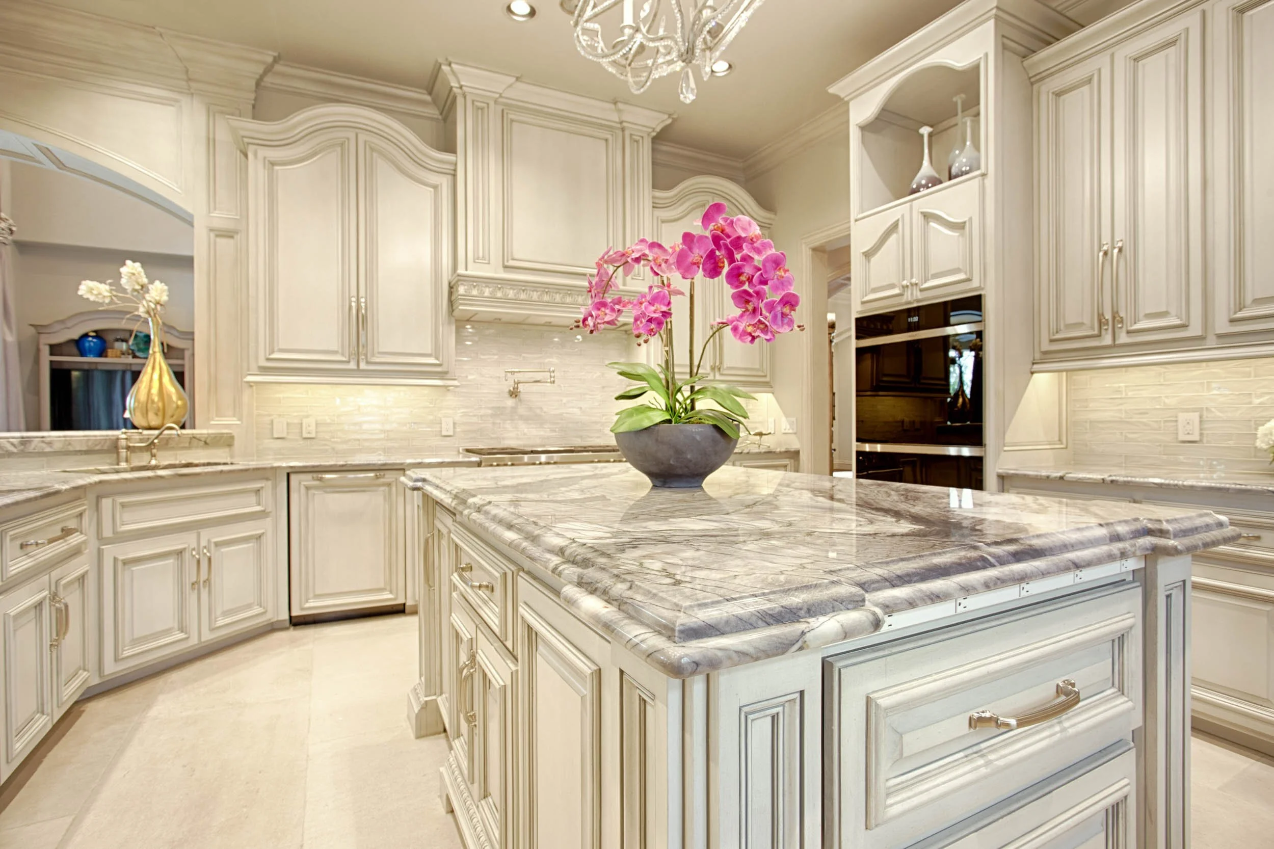  Marble countertops with white cabinets and a plant in the center.  