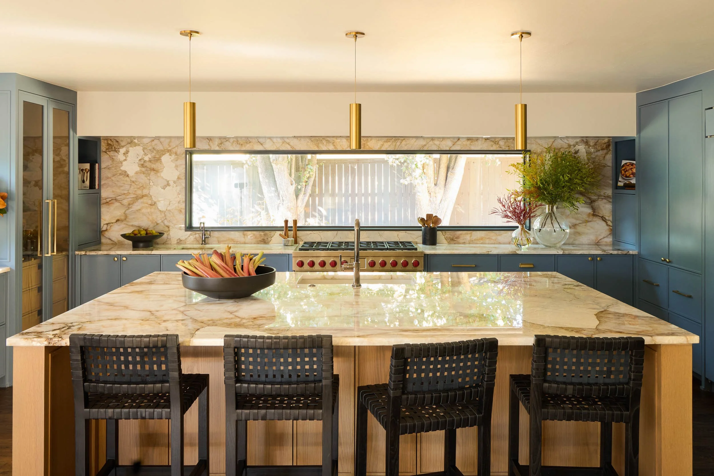  Kitchen countertops with brown chairs, blue cabinets, gold fixtures and other decor items.  