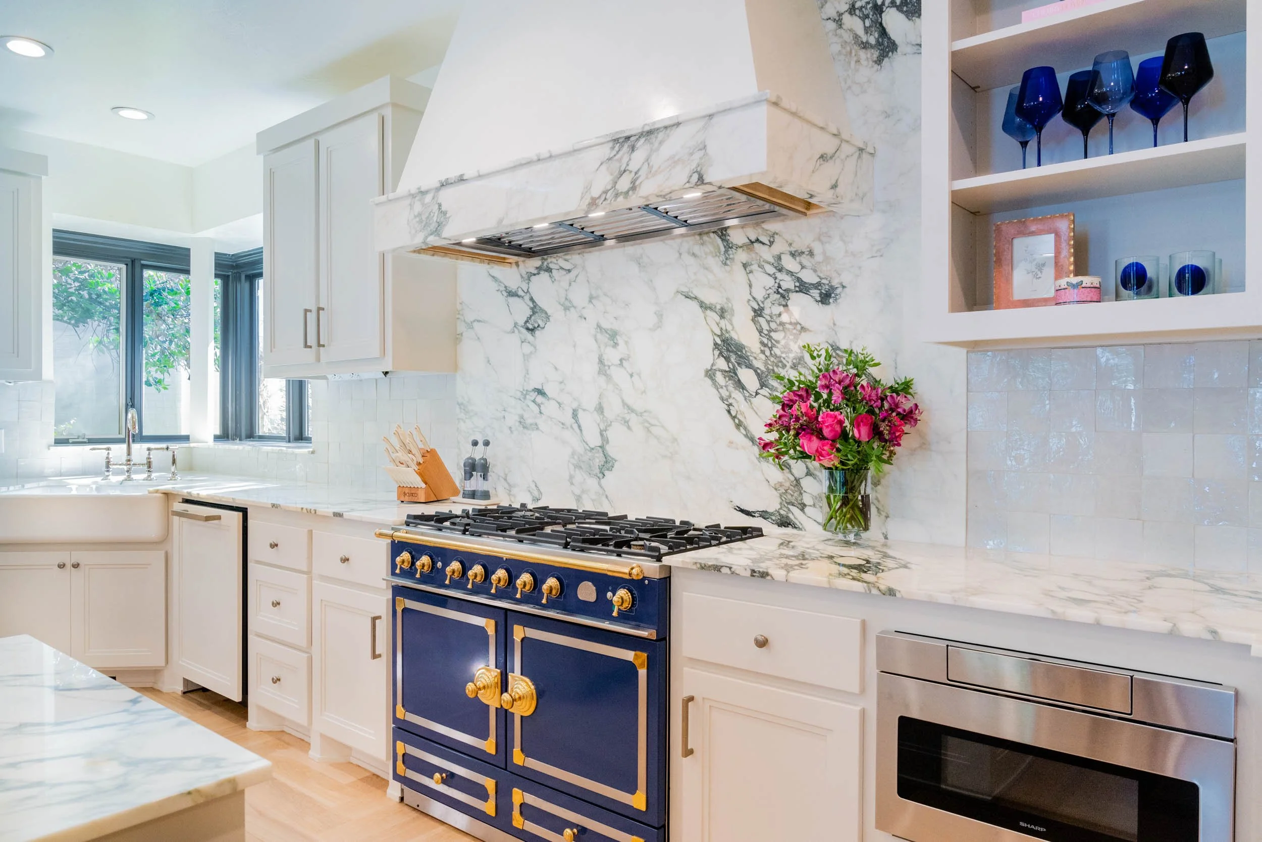  Marble countertops with blue and gold oven and white cabinets.  
