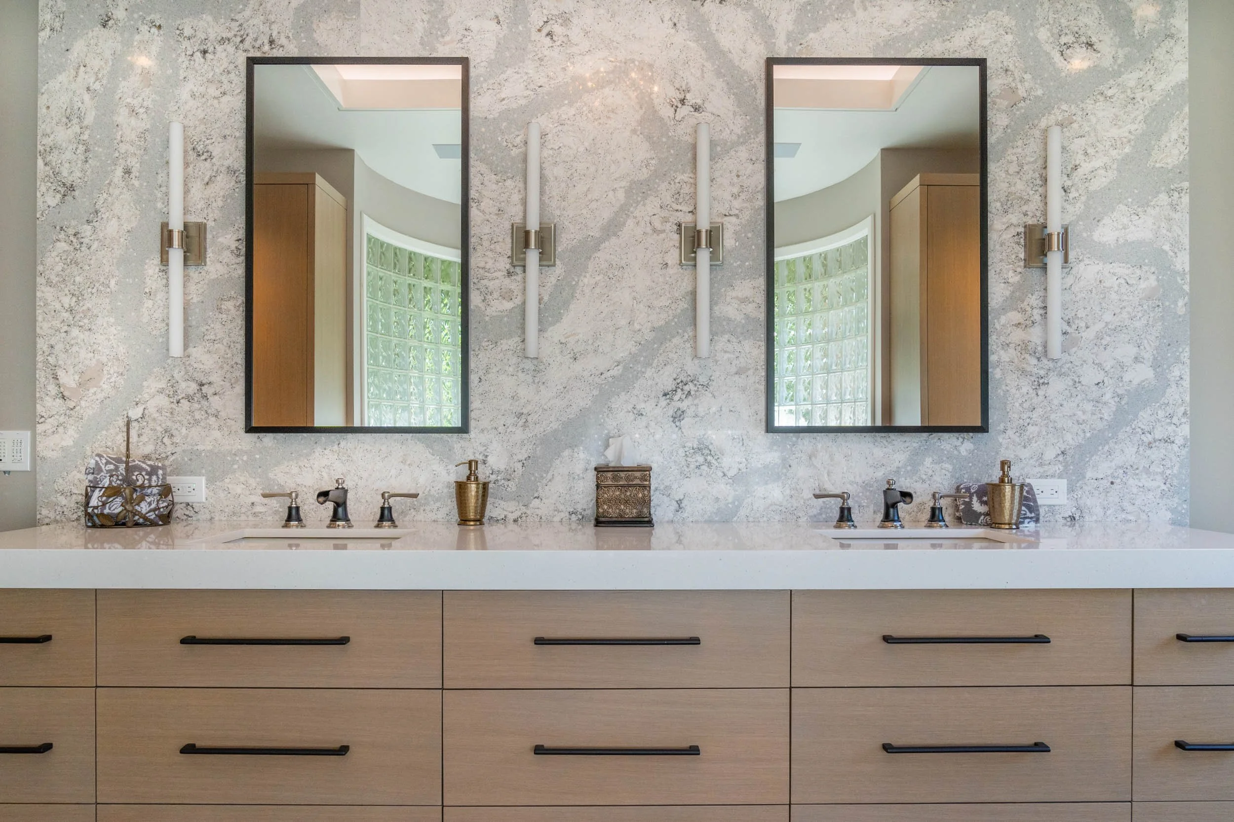  Custom countertops and backsplash with wood cabinetry and two large mirrors. 