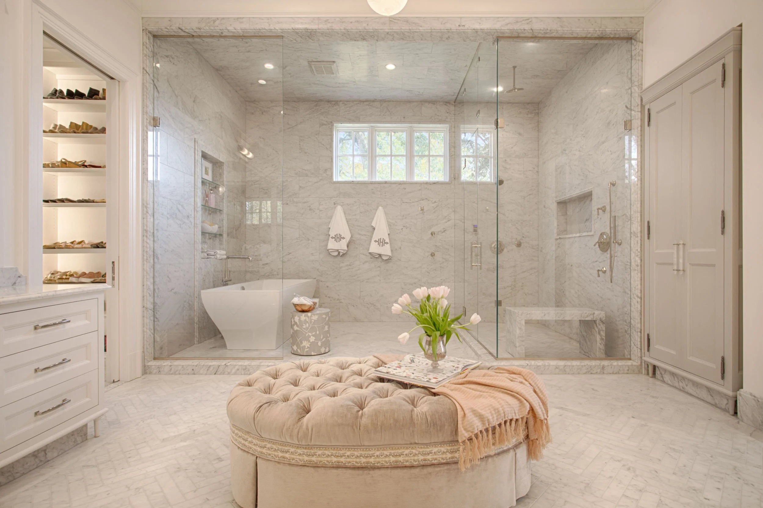  A bathroom with custom tile and a beige ottoman in the center.  