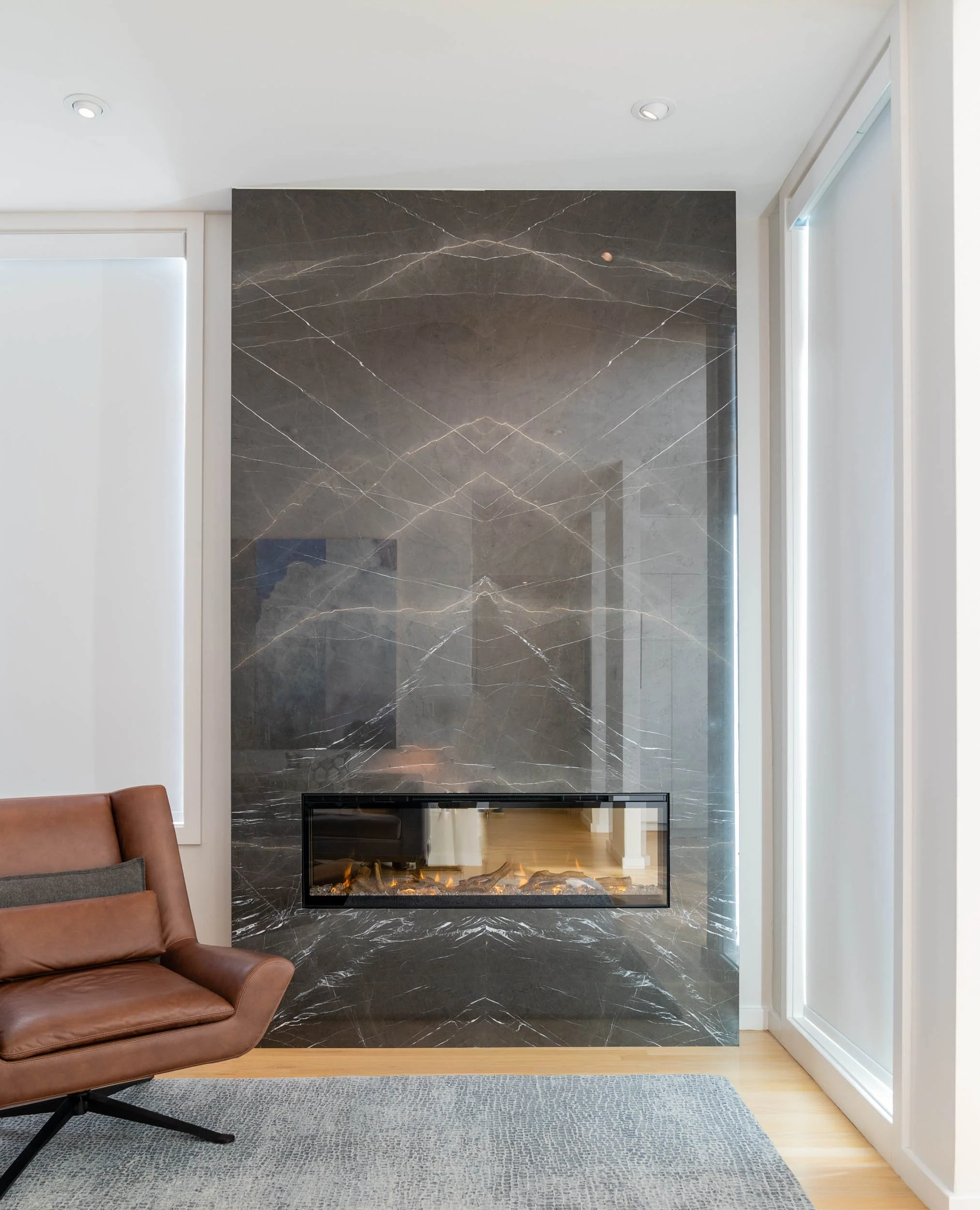  Bookmatched black marble fireplace with brown chair.  