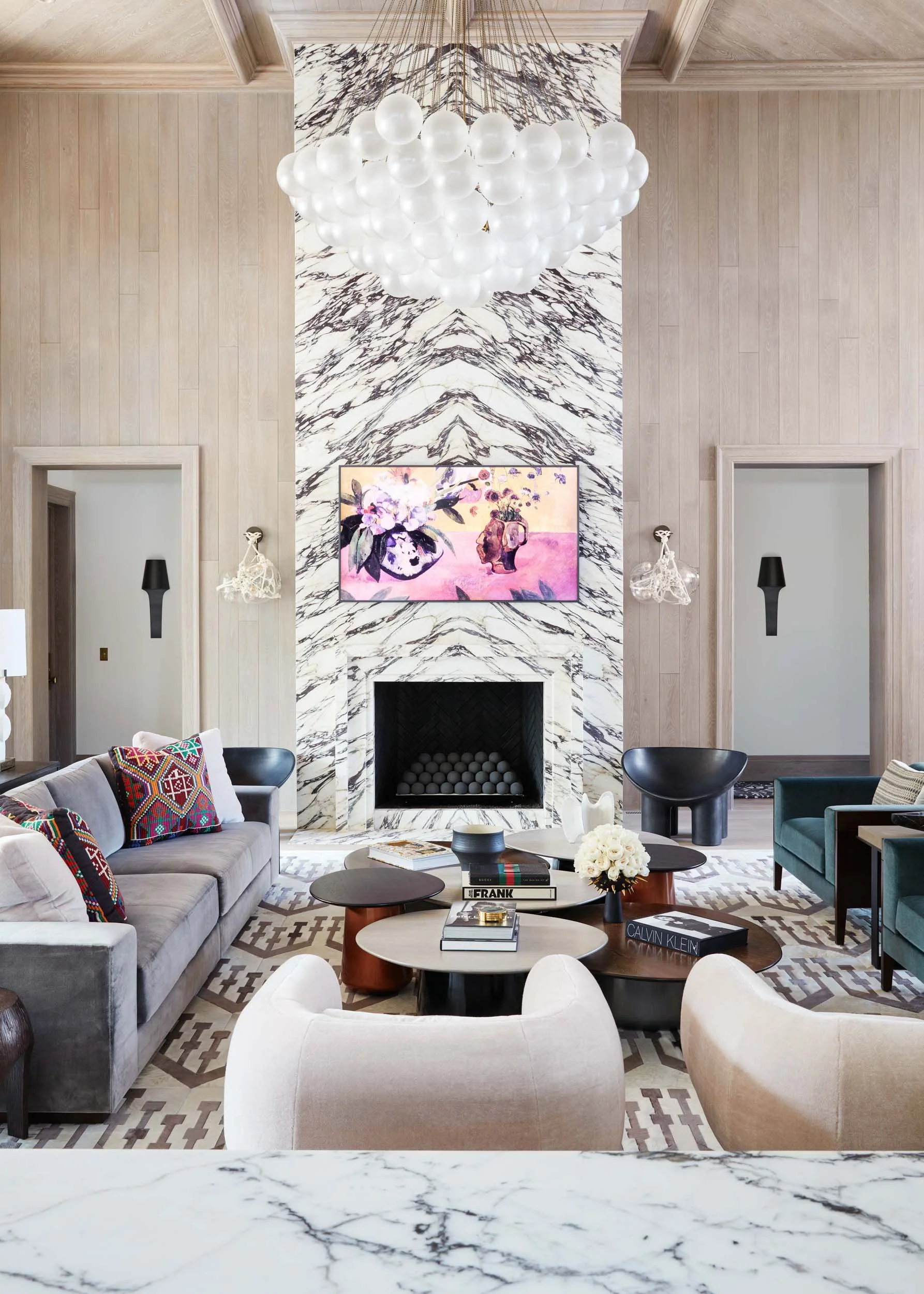  Bookmatched marble fireplace installation in a furnished living room with chandelier.  