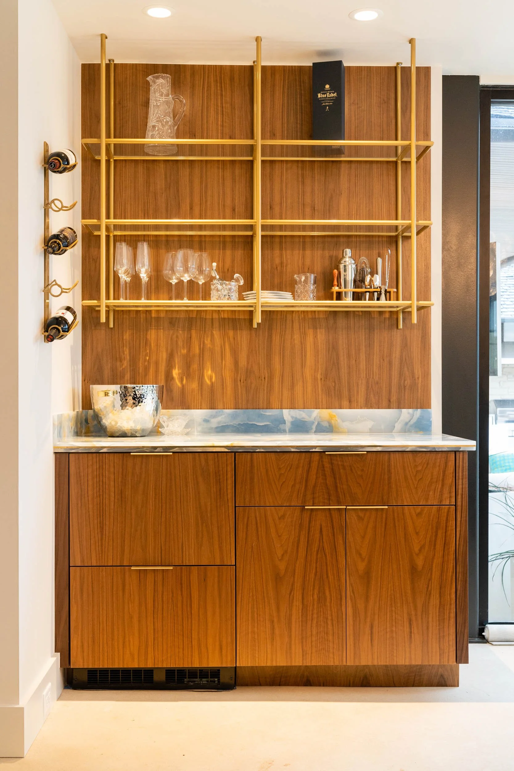  Bar with wood cabinets, gold accents, and marble countertops.  