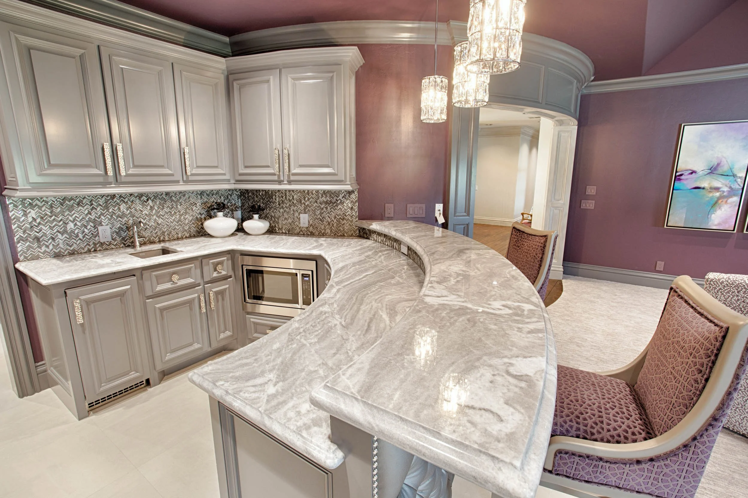  Kitchen with marble countertops, purple chairs and walls, and grey cabinets. 