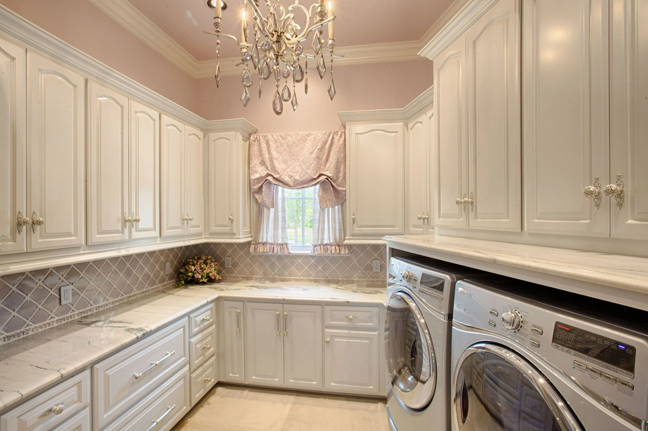  Laundry room with pink walls, marble countertops, and custom tile backsplash.  