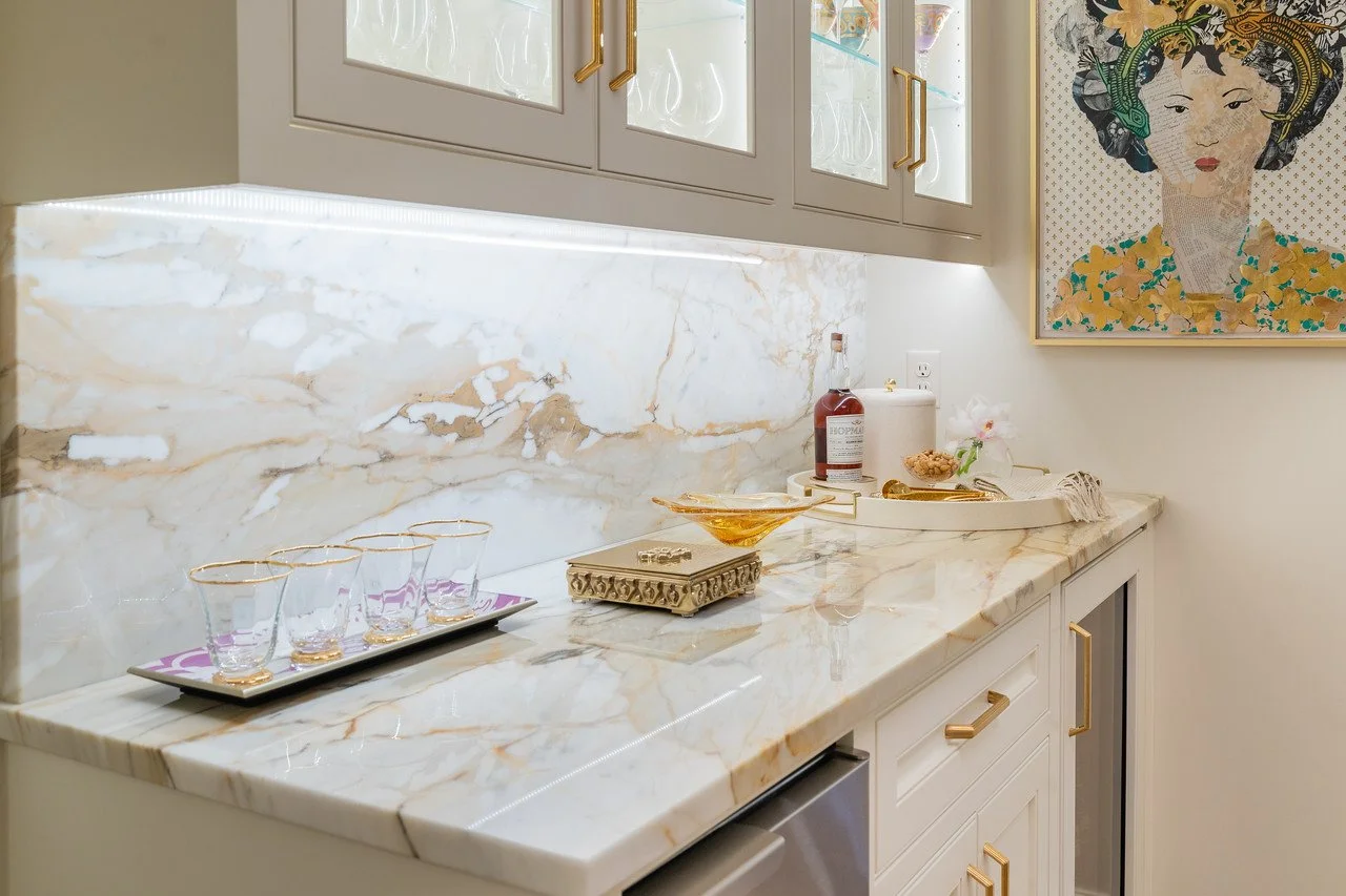  Bar area with marble countertops, white cabinets and other decor items. 