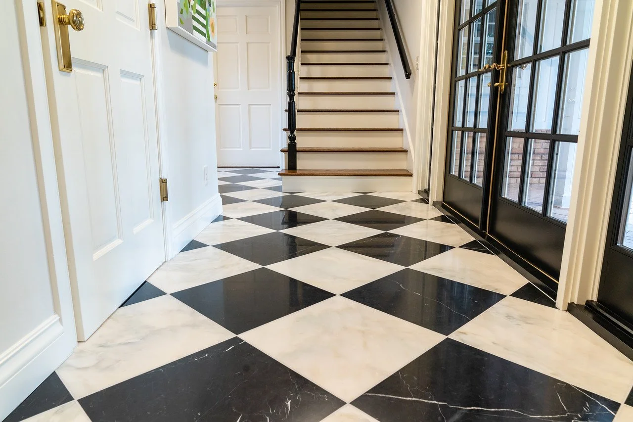 Hallway with custom tile in a checkered pattern in front of a staircase. 