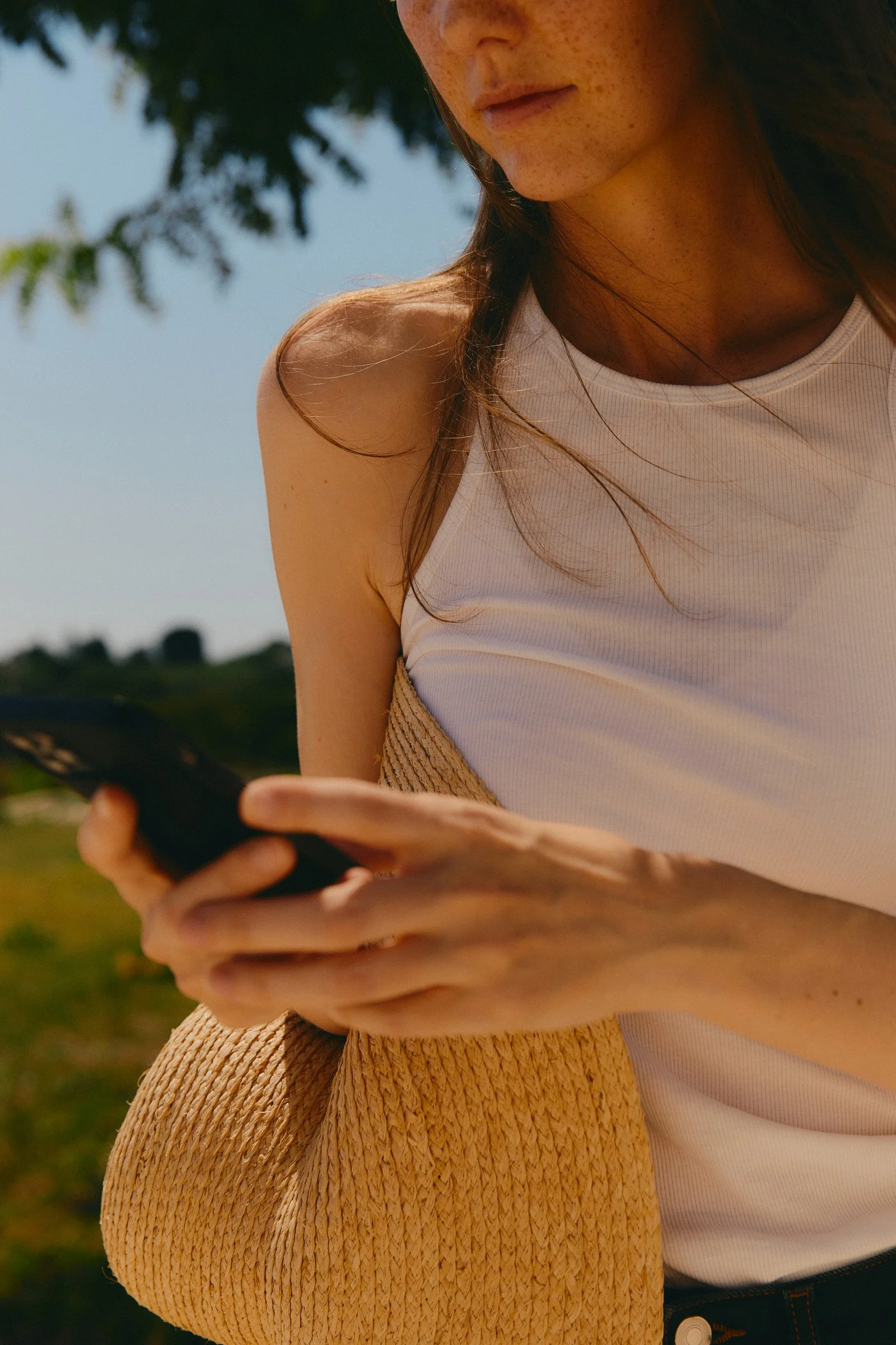 En ung kvinna håller i en smartphone utomhus på dagen.