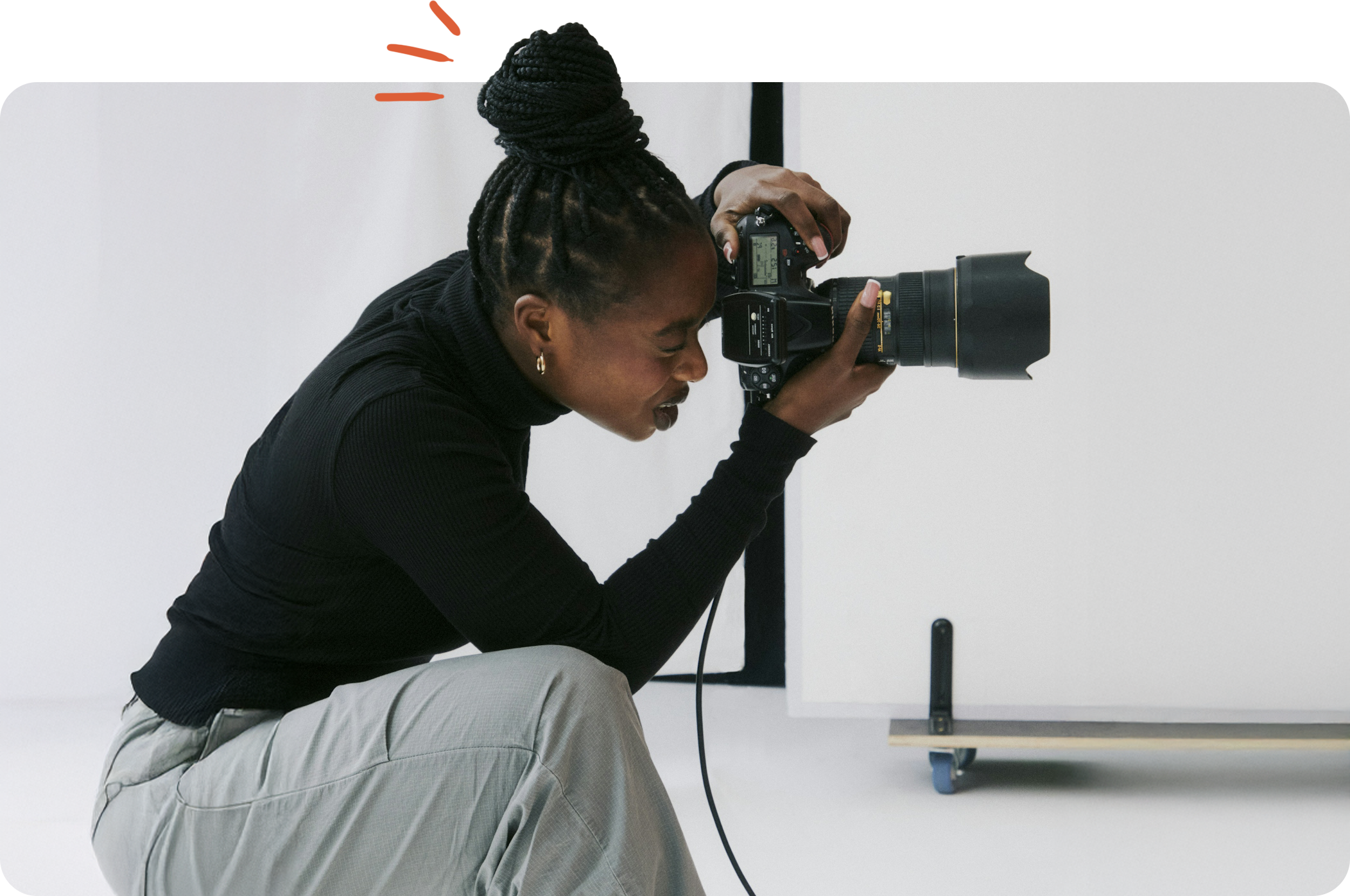 Kvinde med svart hår i dreads som fotograferar med professionell DSLR-kamera i en studio.