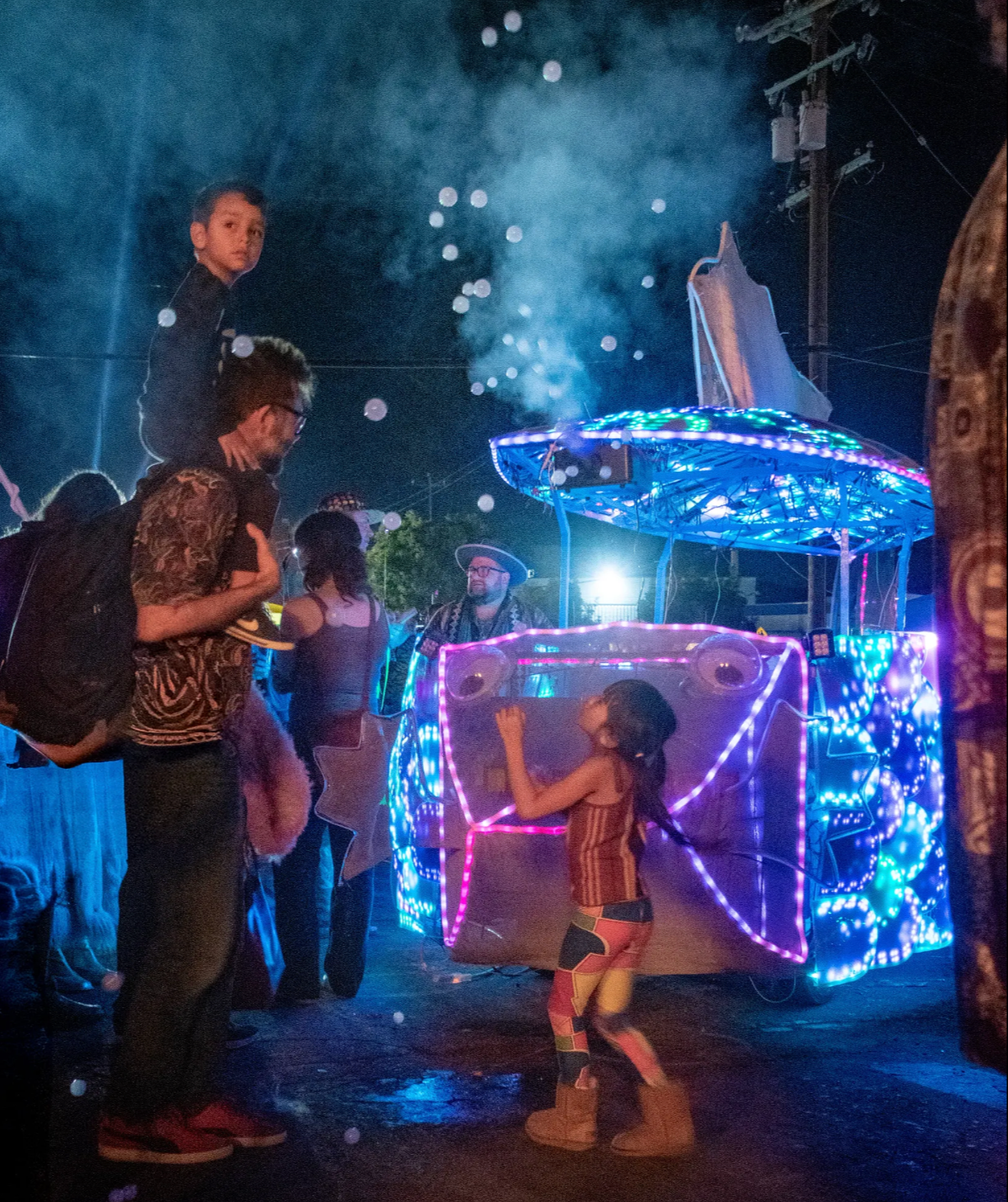 Family playing with Rainbow Fish art car at The Loom Oakland for Burning Man Decompression 2025.