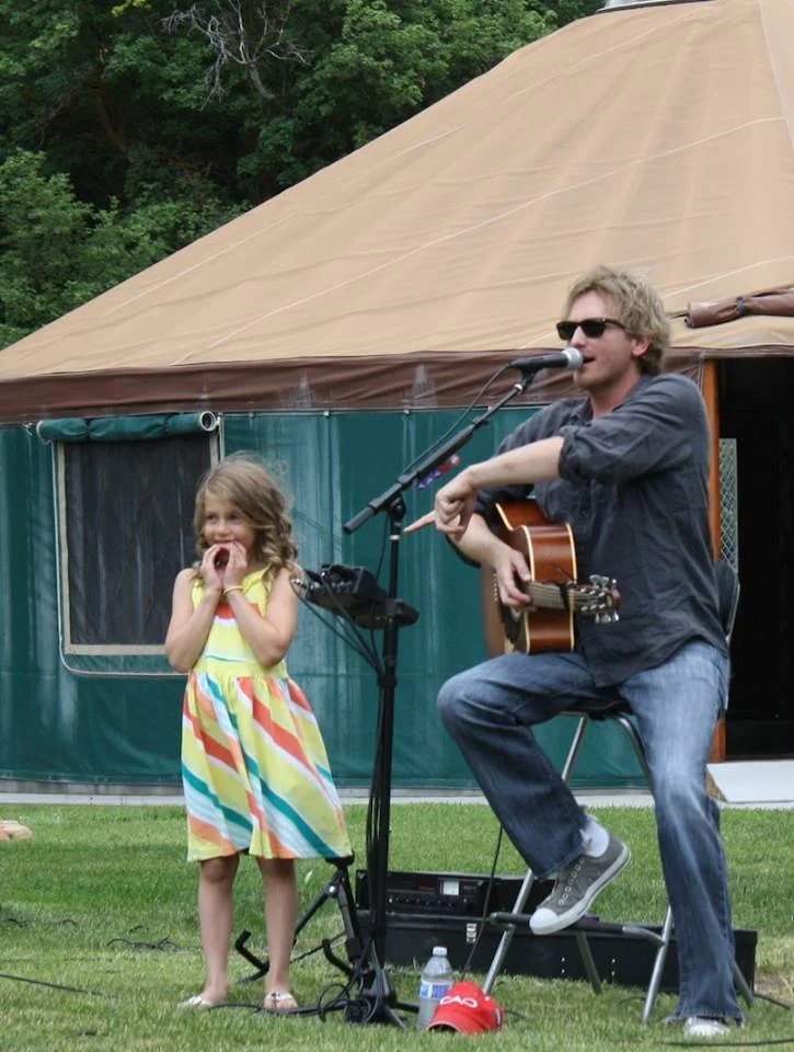 Scott Helmer performs during a benefit concert for the Kostopulos Dream Foundation while a young attendee stands beside him in Salt Lake City, Utah.