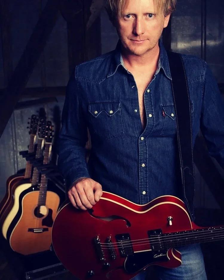 Promotional portrait of American singer-songwriter Scott Helmer holding a red electric guitar.
