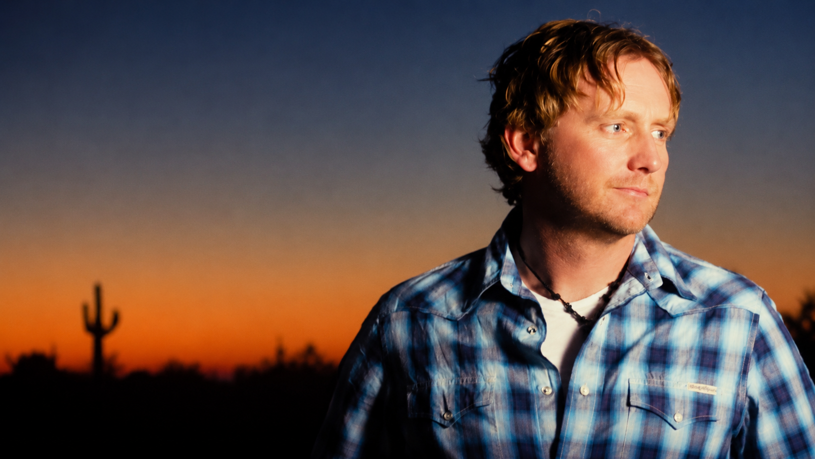 Promotional portrait of American singer-songwriter Scott Helmer outdoors at sunset.