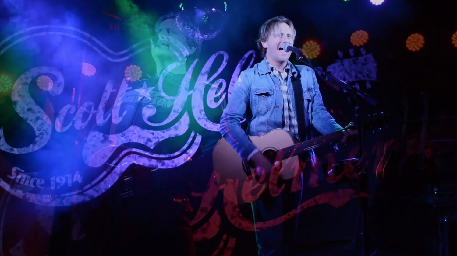 American singer-songwriter Scott Helmer performing live on stage during a concert.