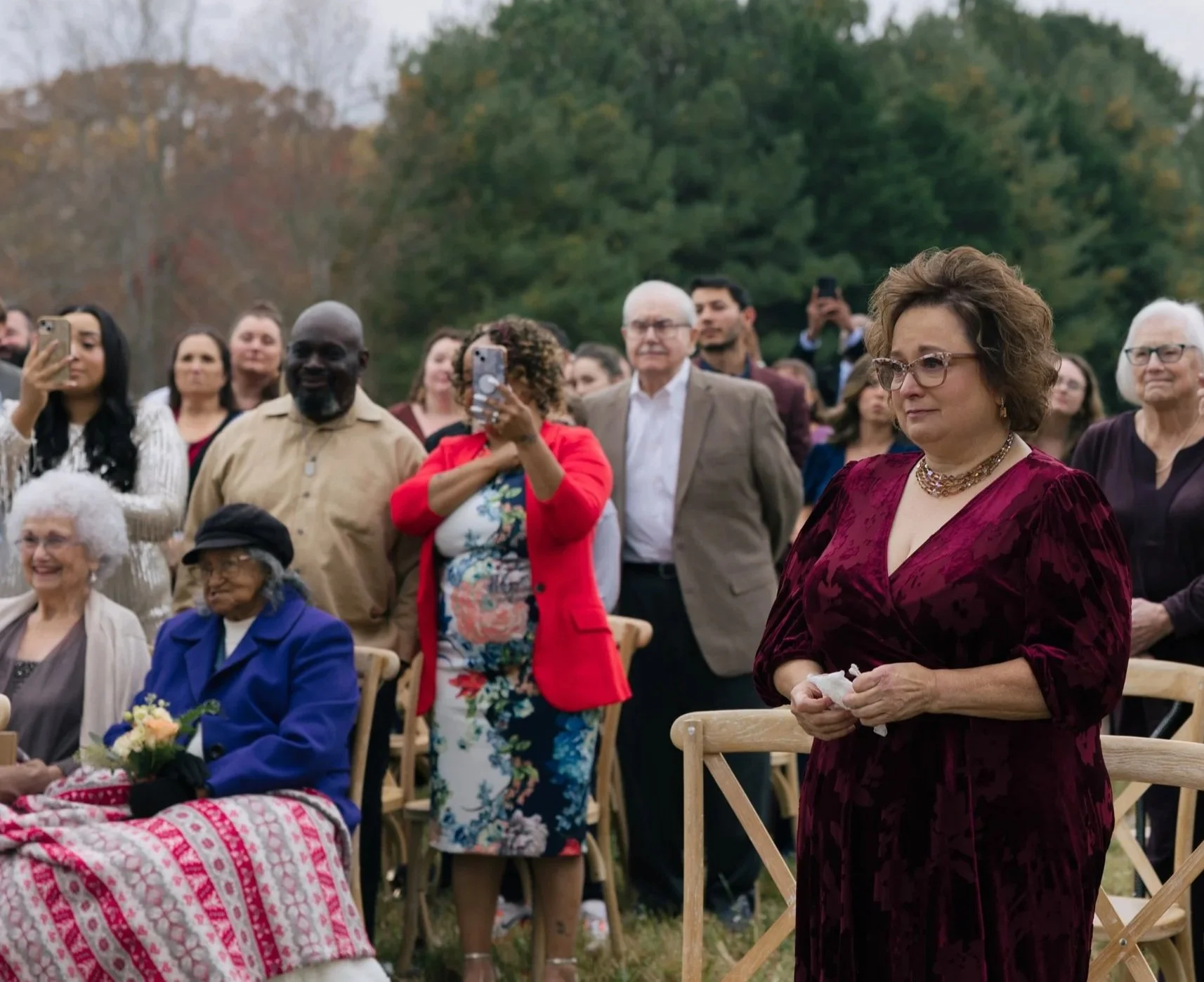 mother looking proud and emotional as her daughter walks down the aisle. Proud family members are in the crowd.