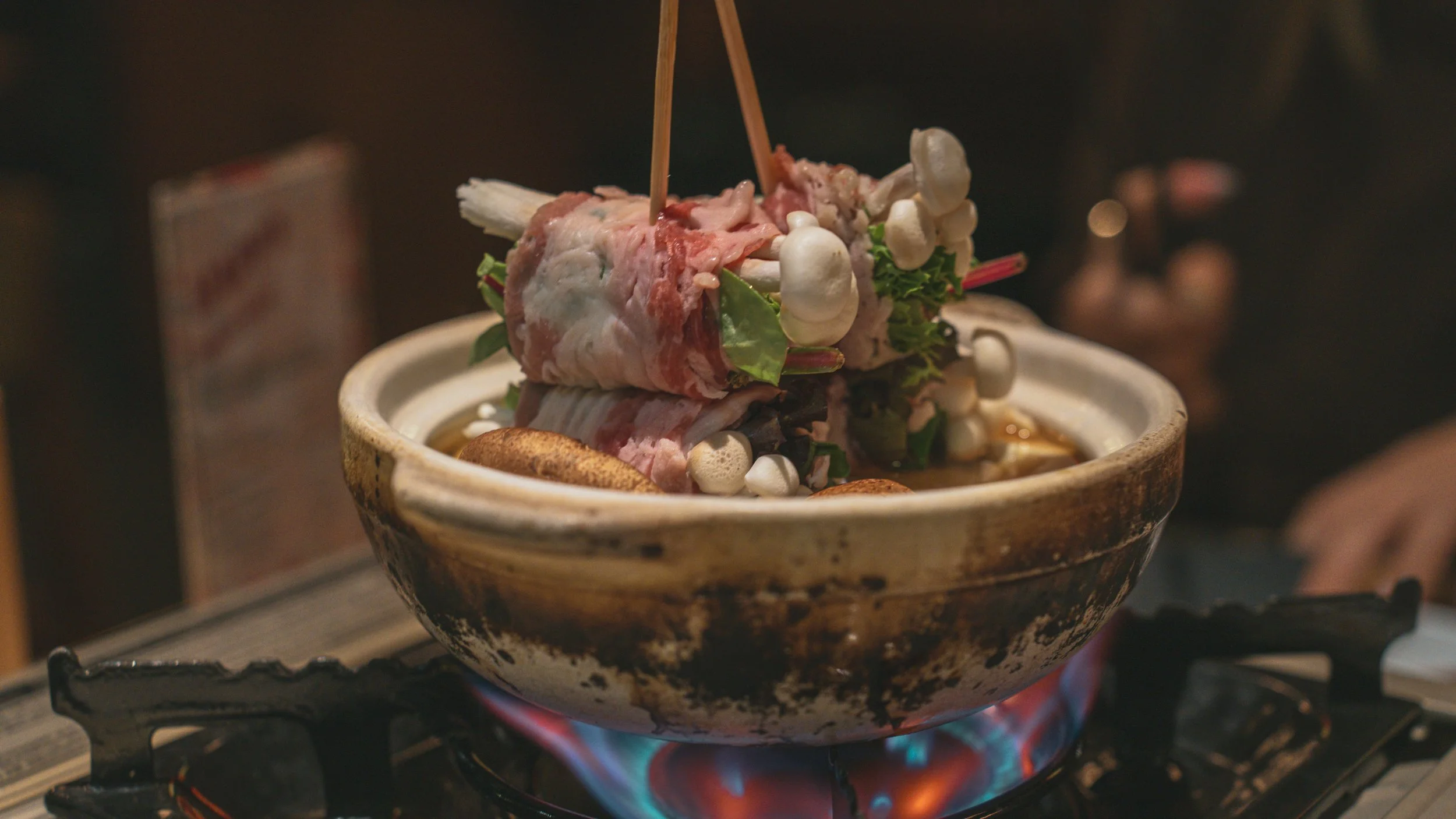 Source: Unsplash A Japanese hot pot featuring thinly sliced pork, fresh vegetables, and mushrooms simmering in broth at a local restaurant in Tokyo.
