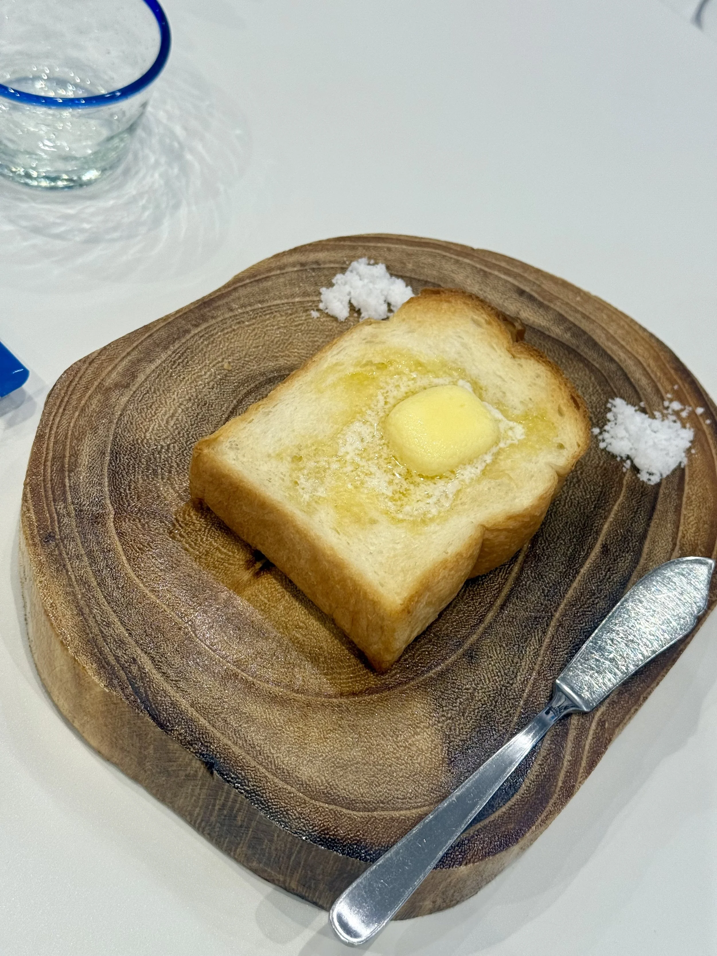 Thick slice of buttered toast served with small portions of salt during the Guruguru Shakashaka salt making experience in Tokyo. Visitors can compare different salt blends and discover how they enhance the flavor of the toast.