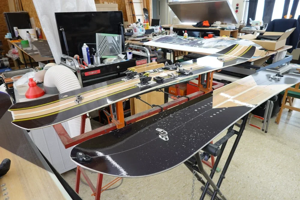 Two wooden snowboards rest on top of gear table in a woodworking studio in Niigata, Japan.