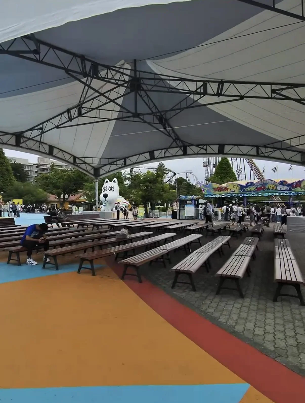 Covered seating area at Yomiuriland with picnic tables and nearby attractions. The shaded rest area provides a comfortable place for visitors to relax during their visit.