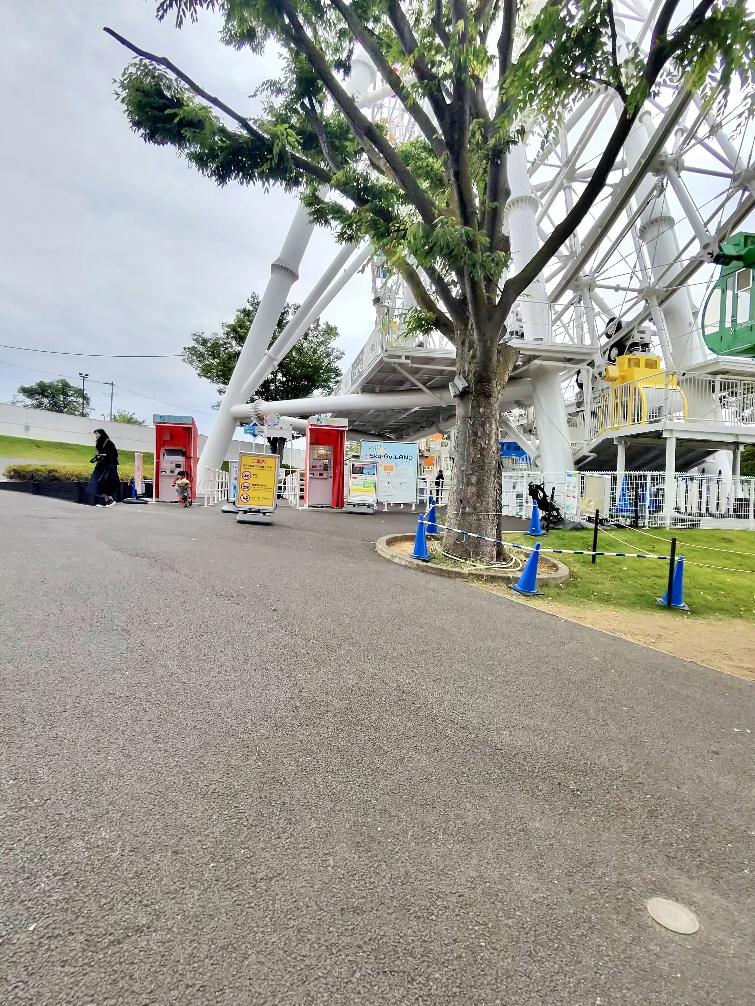 Wide paved pathway near the Ferris wheel at Yomiuriland with step free access and open space for visitors. The accessible walkway makes it easier for wheelchair users, strollers, and guests with mobility needs to move around the park.