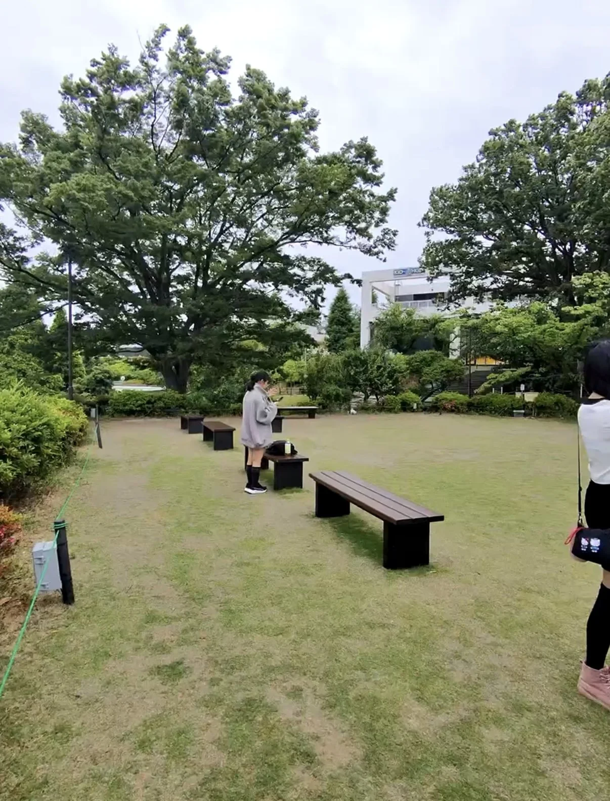 Peaceful garden at Yomiuriland with grassy lawns, large trees, and benches for visitors to rest. The landscaped area offers a quiet place to relax between attractions.