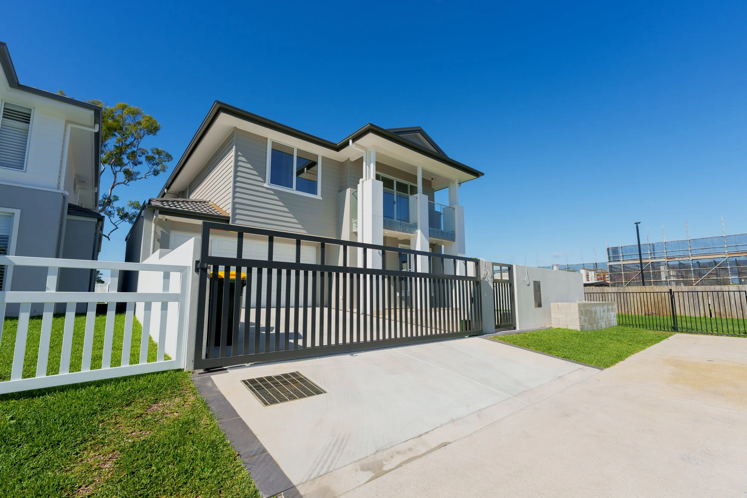 Dark vertical-slat driveway gate installed at a modern home