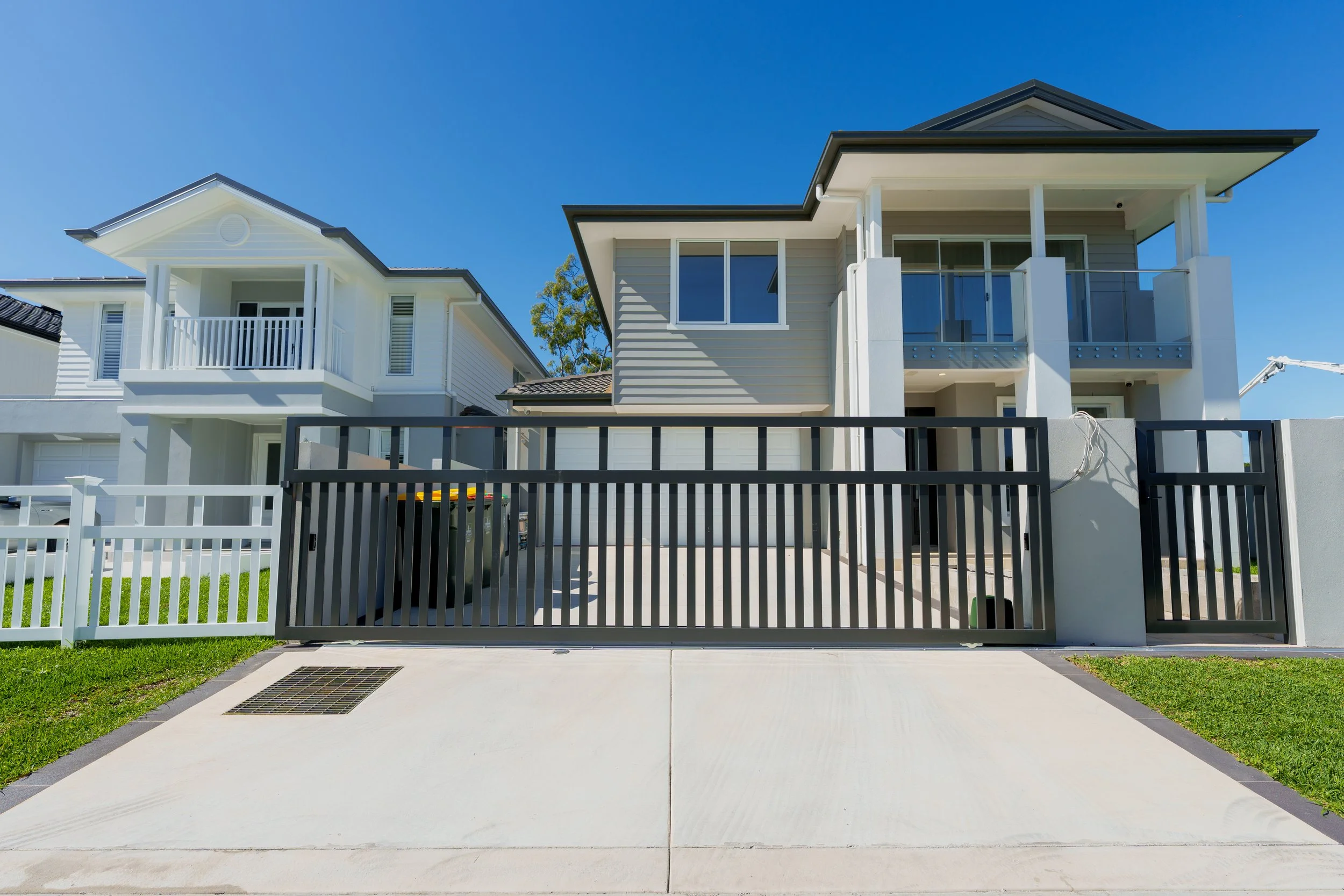 Dark grey vertical-slat sliding gate across a residential driveway